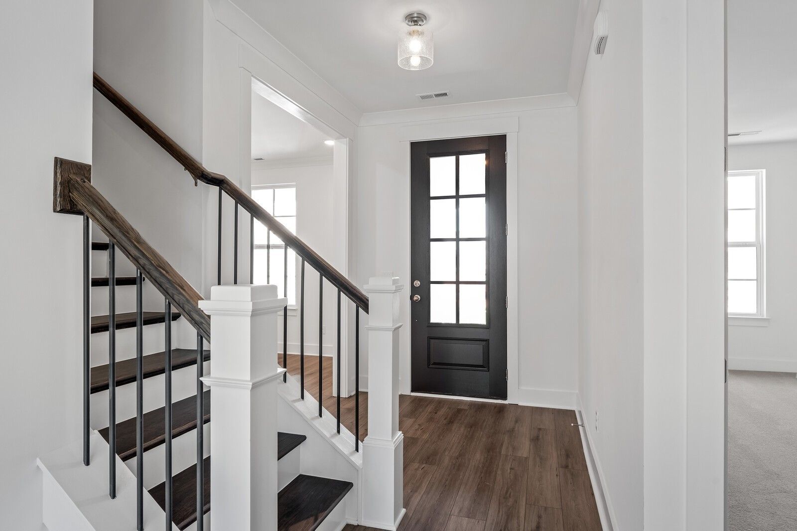 Elegant wooden staircase with black iron balusters and dark glass door in The Hawkins 2-story home, Shelton Square, Murfreesboro, Tennessee