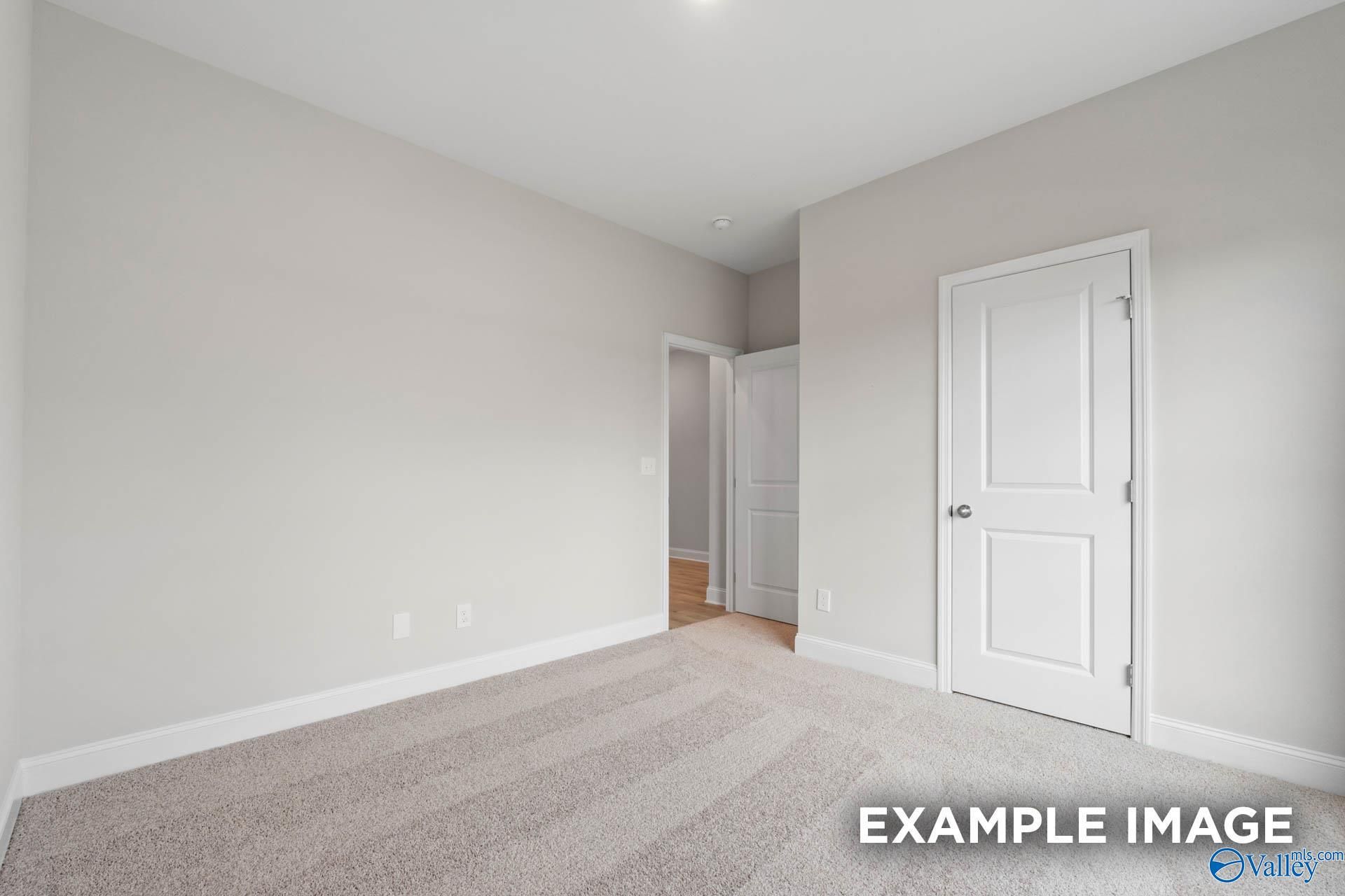 Spacious secondary bedroom with neutral gray walls, white doors, and plush carpet in Davidson Homes The Franklin V, Athens, Alabama