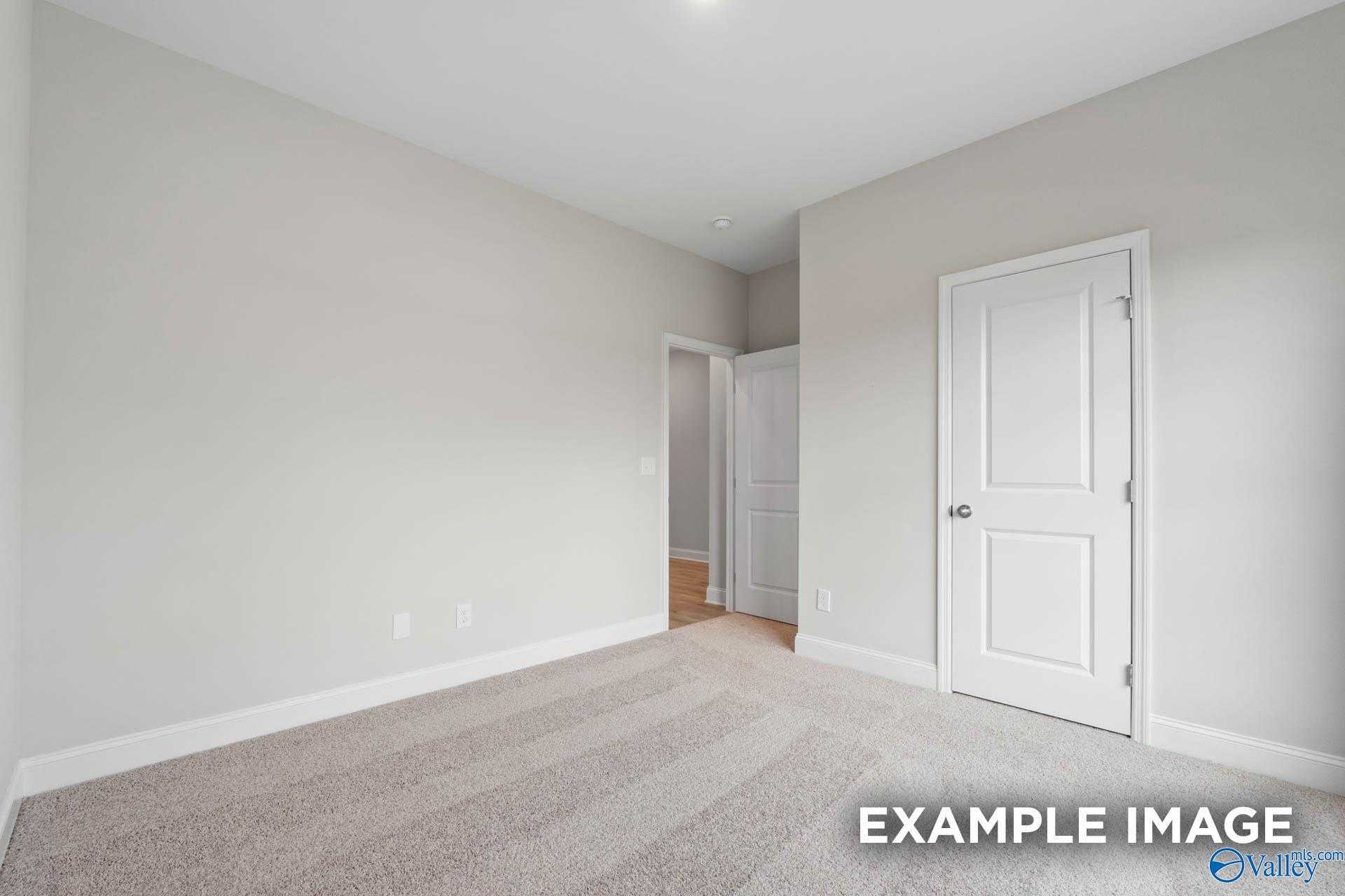 Spacious secondary bedroom with neutral gray walls, white doors, and plush carpet in Davidson Homes The Franklin V, Athens, Alabama