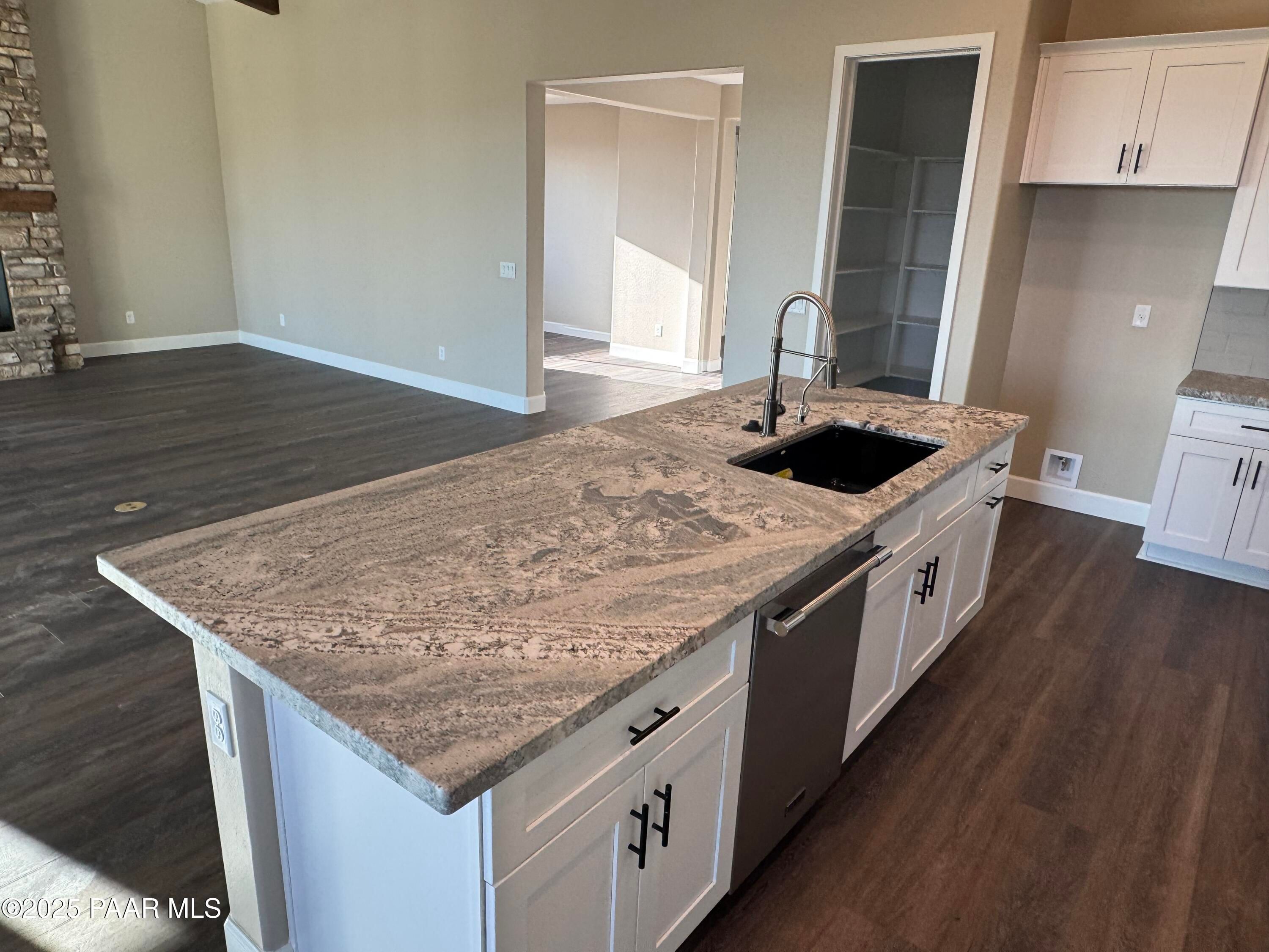 Modern kitchen island with granite countertop, stainless sink and dishwasher in Evermore Homes Sunrise A, Prescott Valley, AZ
