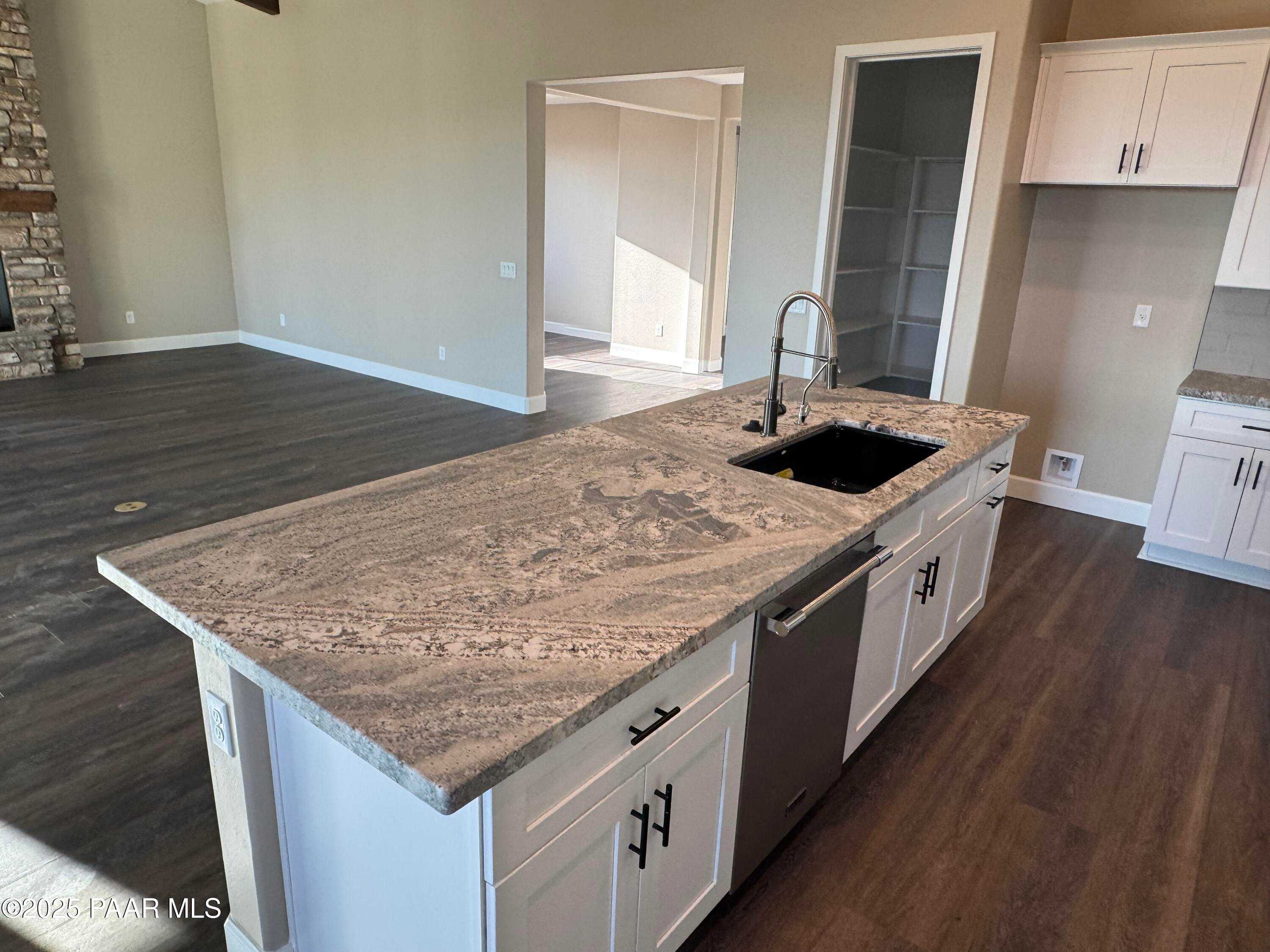 Modern kitchen island with granite countertop, stainless sink and dishwasher in Evermore Homes Sunrise A, Prescott Valley, AZ