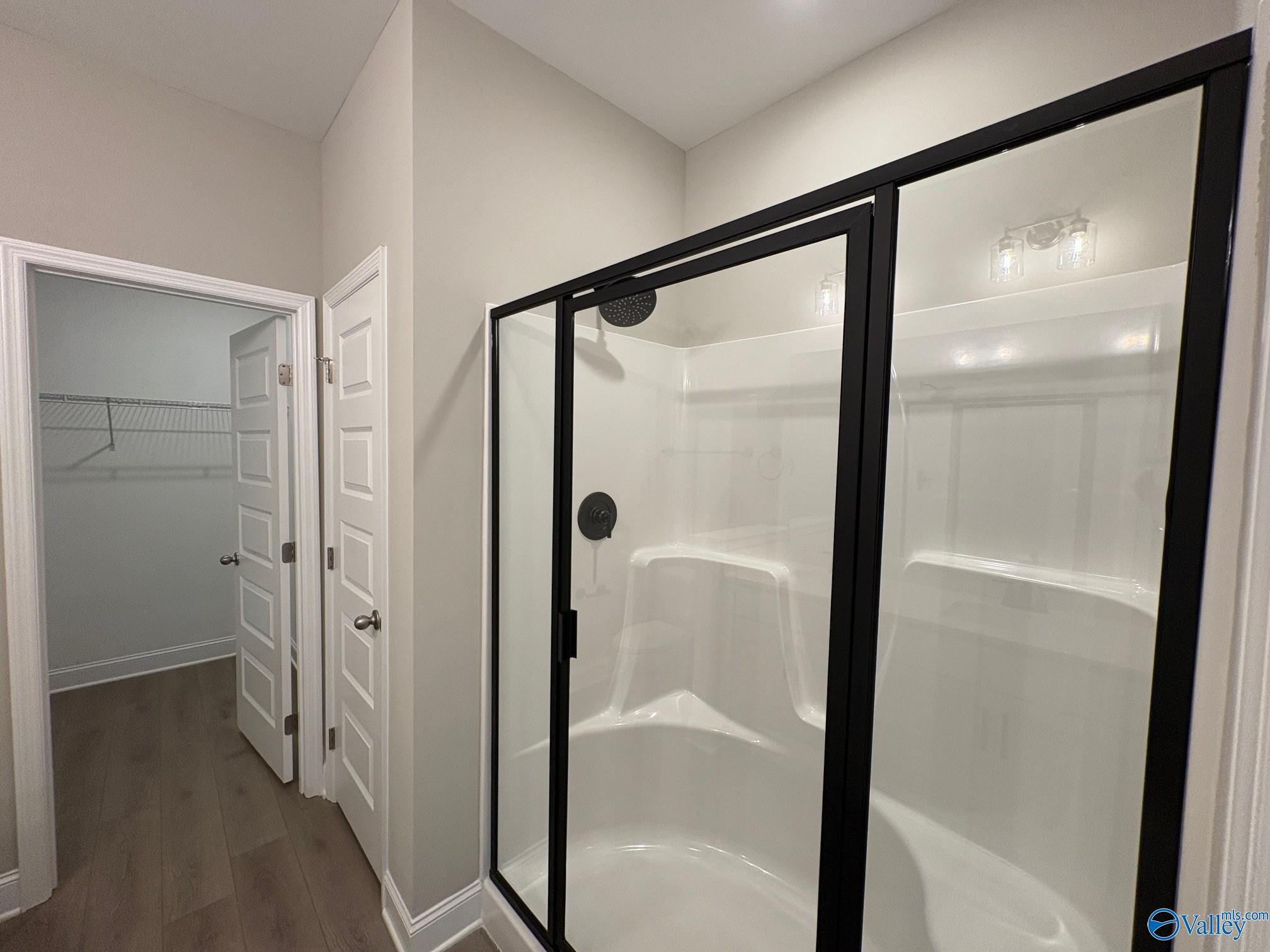 Modern master bathroom with frameless glass shower and adjacent walk-in closet in The Asheville C, Arab, Alabama
