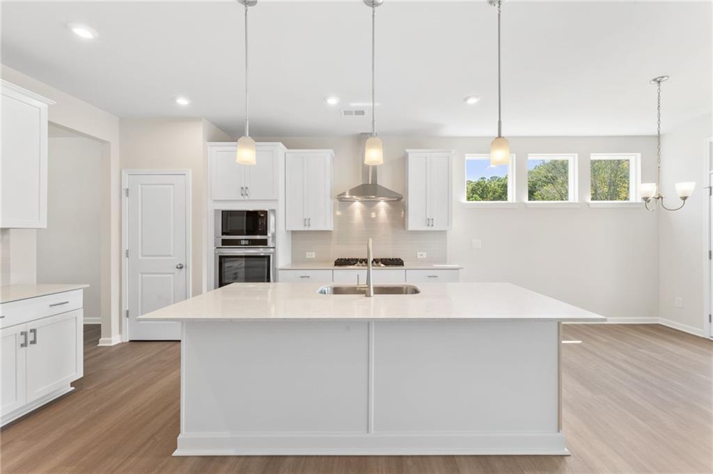 Spacious modern kitchen with white island, stainless appliances, pendant lights in 3-bedroom Davidson Homes The Ash B, Riverwood, Dallas, GA