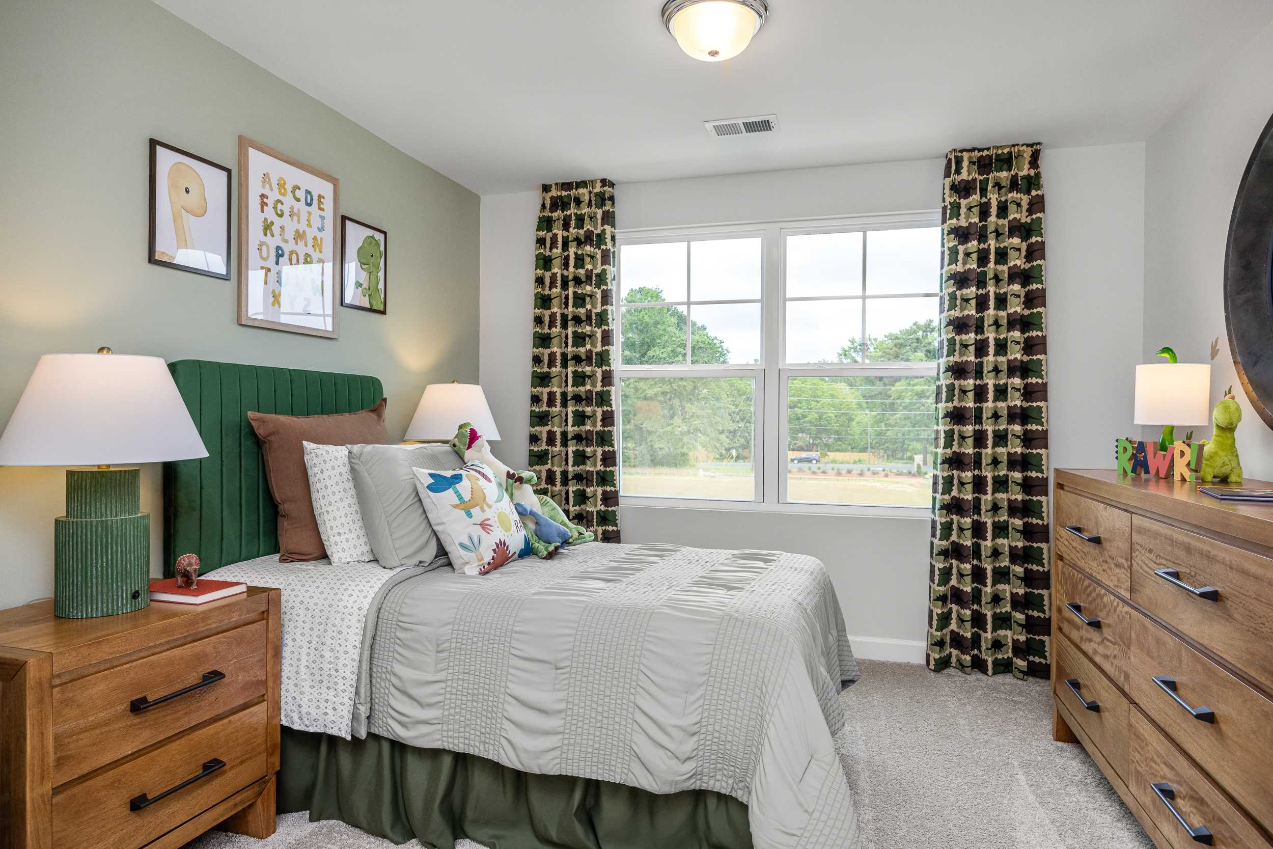 Cozy child's bedroom in Springvale Fuquay-Varina NC with green headboard bed, colorful pillows, ABC wall art and tree-view window