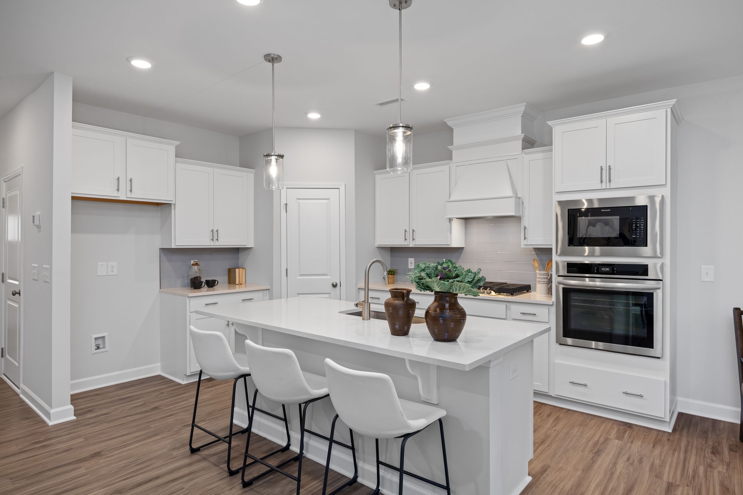 Modern kitchen in The Warren featuring white cabinets, quartz island, stainless steel appliances, and pendant lighting.