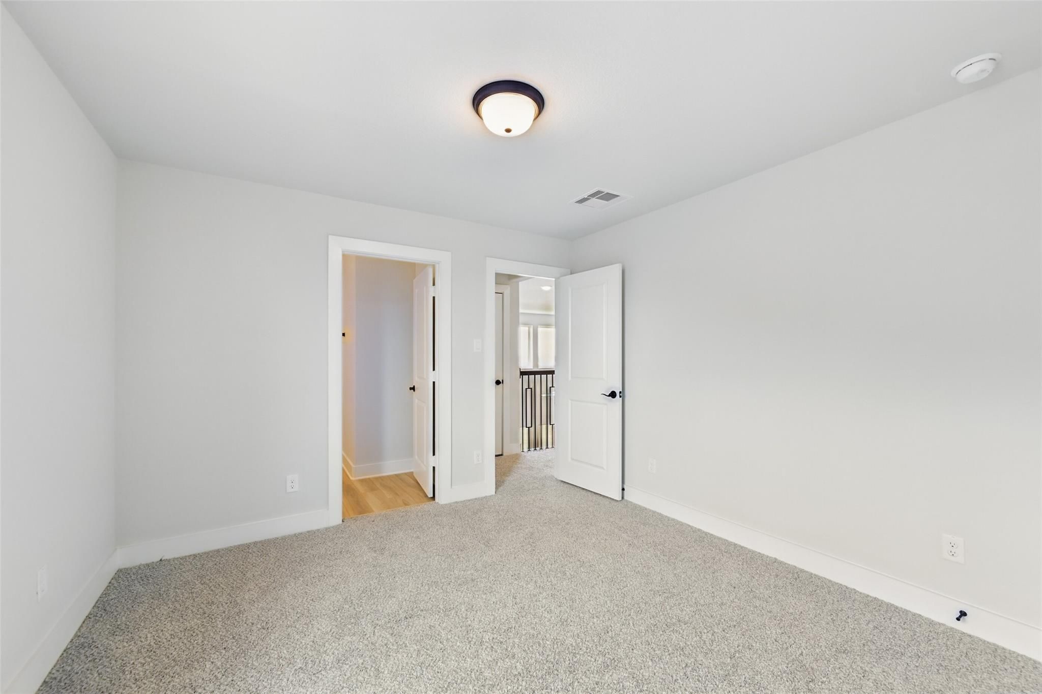Spacious upstairs bedroom with gray carpet, white walls, and open doors to hallway in Davidson Homes The Victoria C, Lago Mar, Texas City
