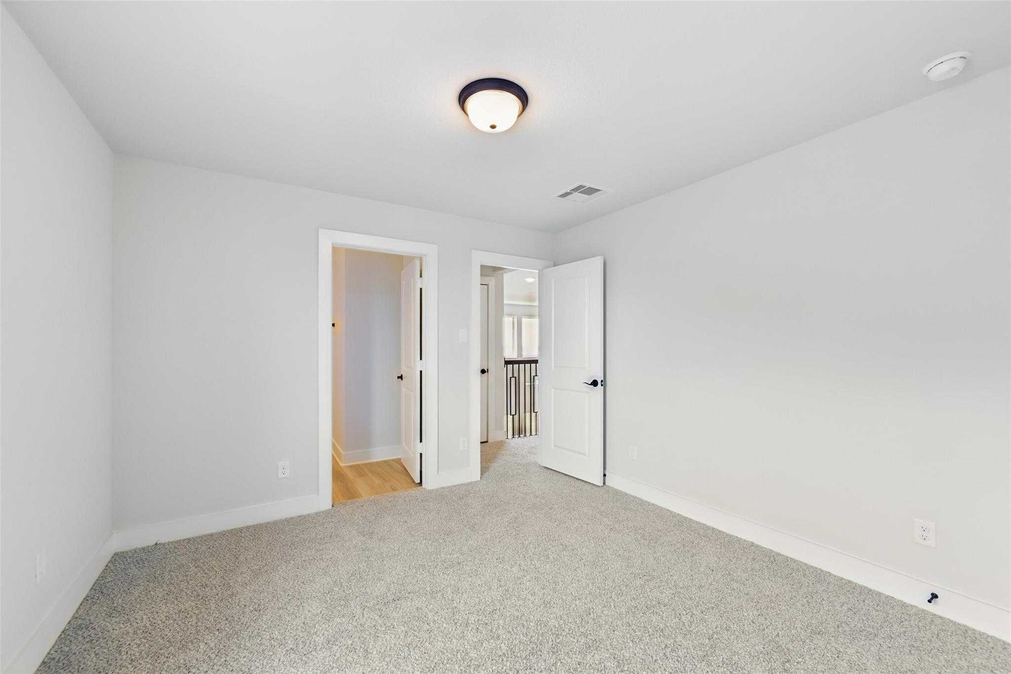 Spacious empty bedroom with light gray walls, gray carpet, and balcony access door in Davidson Homes The Victoria C, Lago Mar, Texas