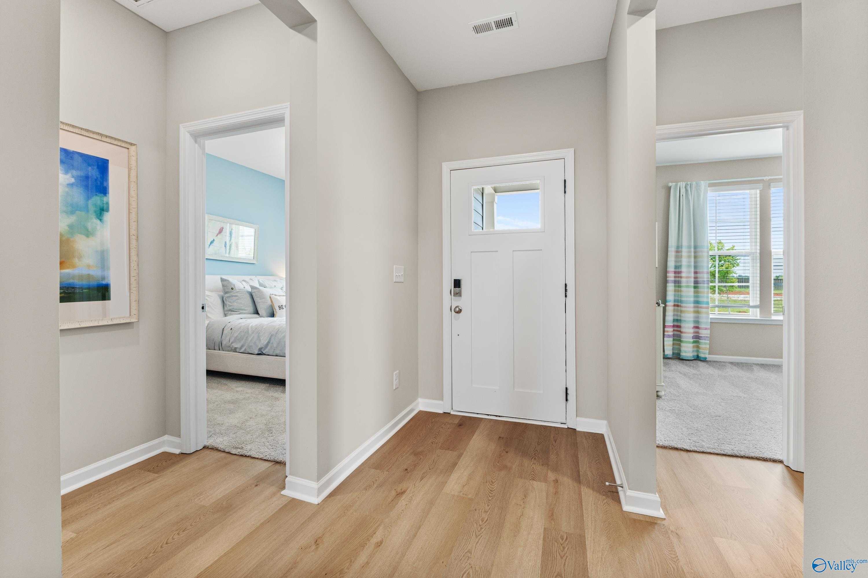 Spacious hallway with open bedroom doors, hardwood floors, and abstract art in Davidson Homes The Sanctuary, Athens AL