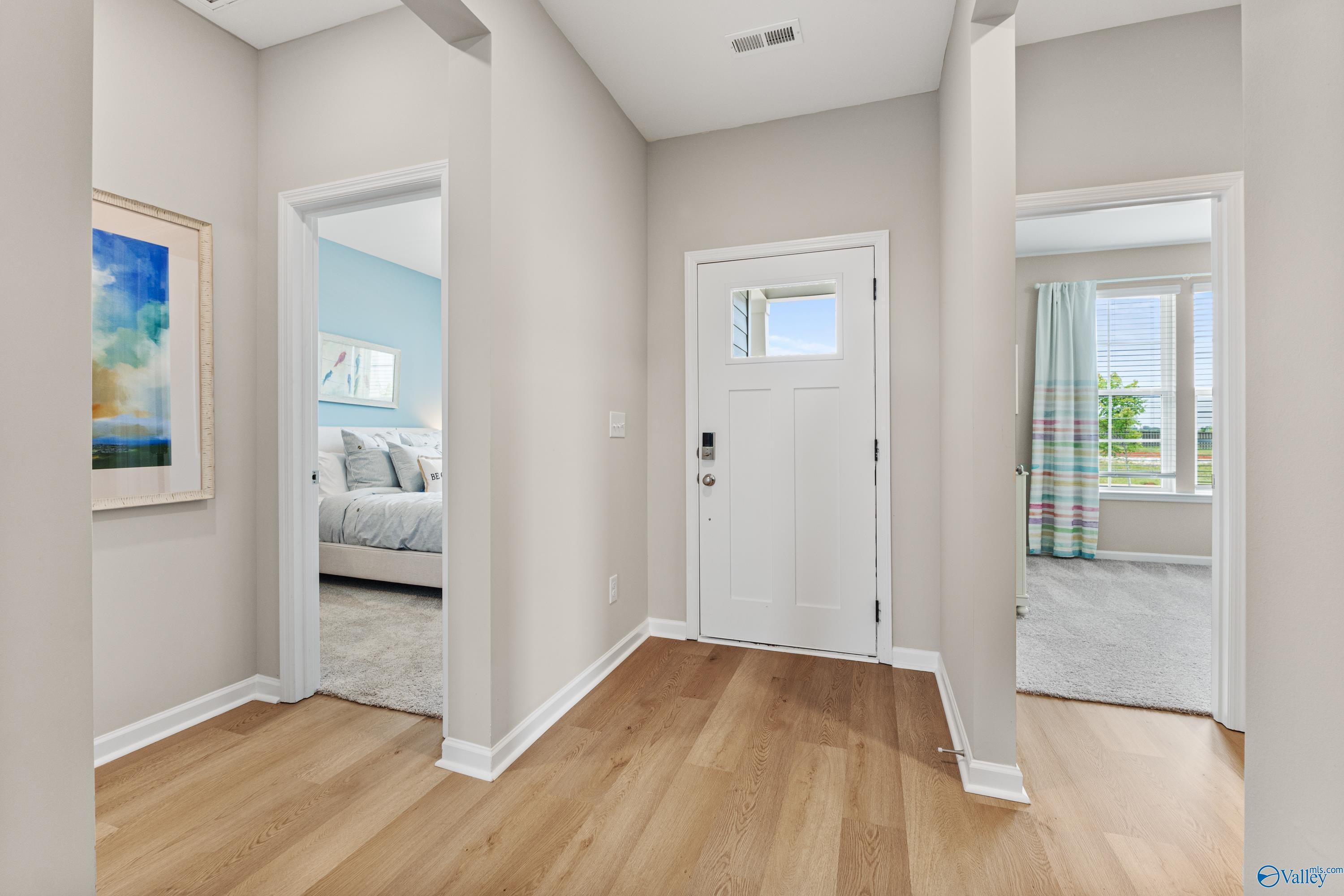 Spacious hallway with open bedroom doors, hardwood floors, and abstract art in Davidson Homes The Sanctuary, Athens AL