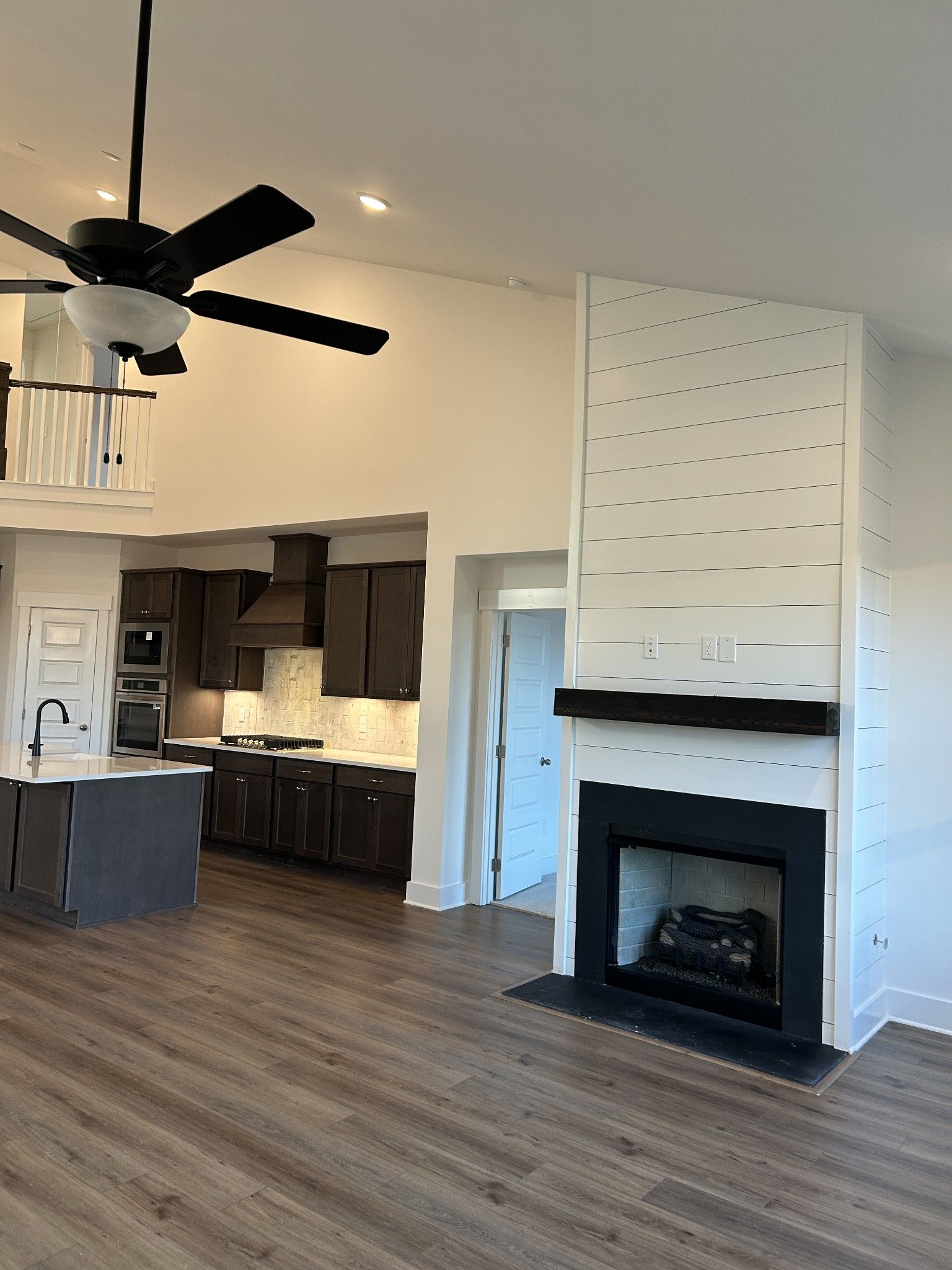 Open-concept living room with shiplap fireplace, modern gray kitchen island, and hardwood floors in Davidson Homes The Ridgeport F, Mt. Juliet