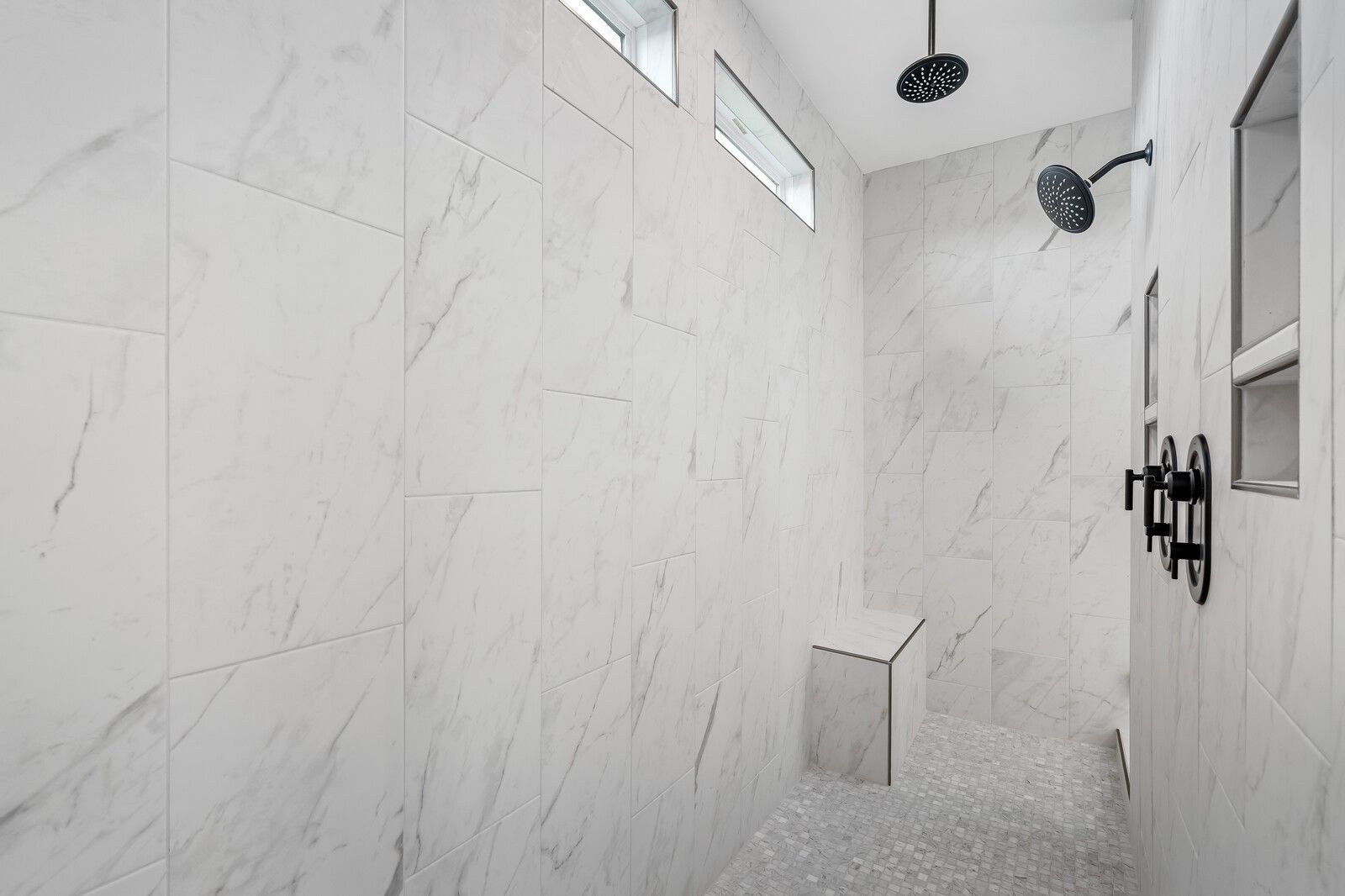 Luxurious master walk-in shower with white subway tiles, dual rain showerheads, black fixtures, and built-in bench in The Alston A, Murfreesboro