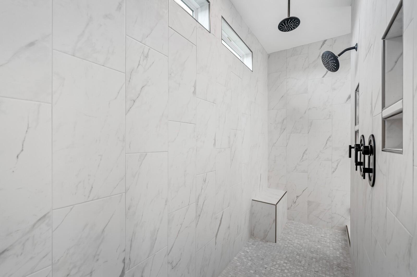 Luxurious master walk-in shower with white subway tiles, dual rain showerheads, black fixtures, and built-in bench in The Alston A, Murfreesboro
