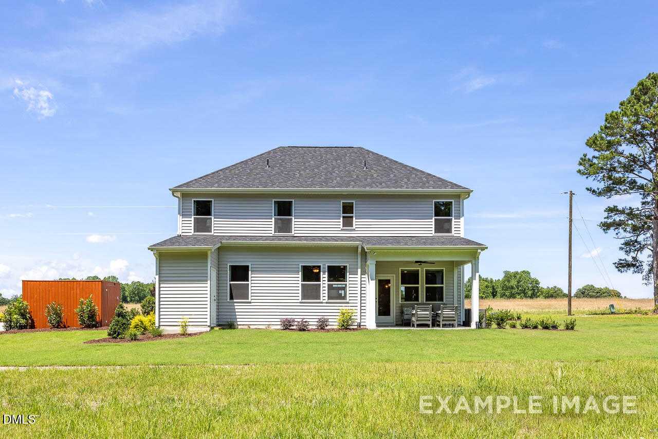 Two-story gray home with wraparound porch, attached garage, and landscaped yard in Retreat at North Main, Lillington, NC - Davidson Homes Willow B