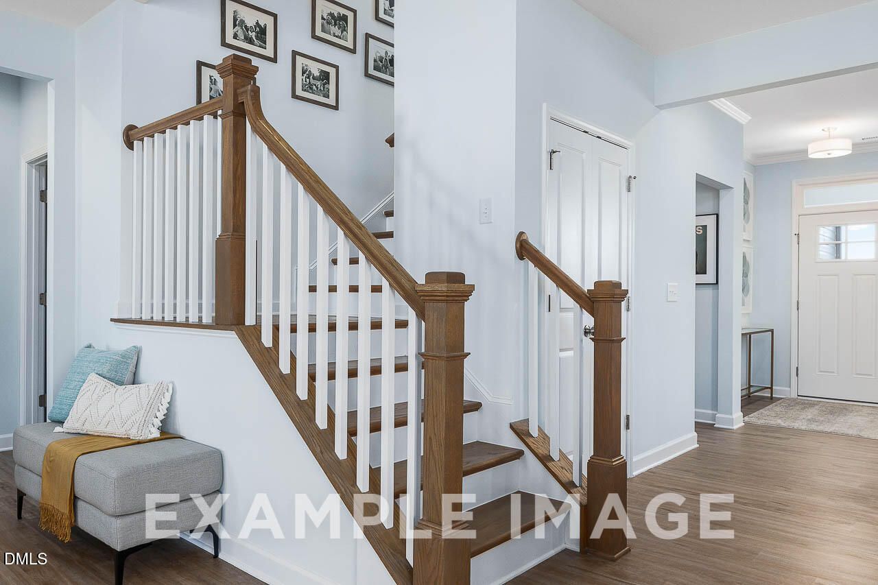 Wooden staircase with white balusters and gallery wall in bright foyer of Davidson Homes' The Ash C in Lillington, NC