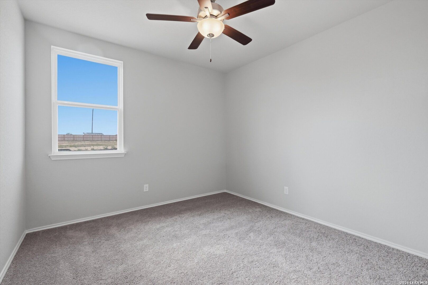 Bright empty bedroom with light gray walls, beige carpet, ceiling fan, and window overlooking blue sky in Davidson Homes The Frio B, San Antonio