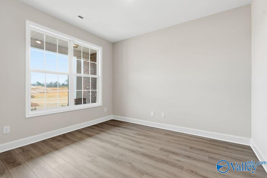 Bright bedroom with large windows, neutral walls, and hardwood floors in Davidson Homes The Rockford B, Hartselle, Alabama