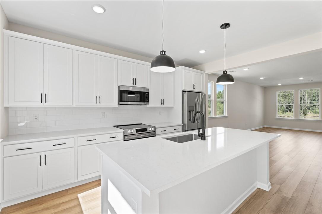 Modern kitchen with white cabinets, quartz island, and pendant lighting in The Stella C plan at Links Crossing, Auburn.