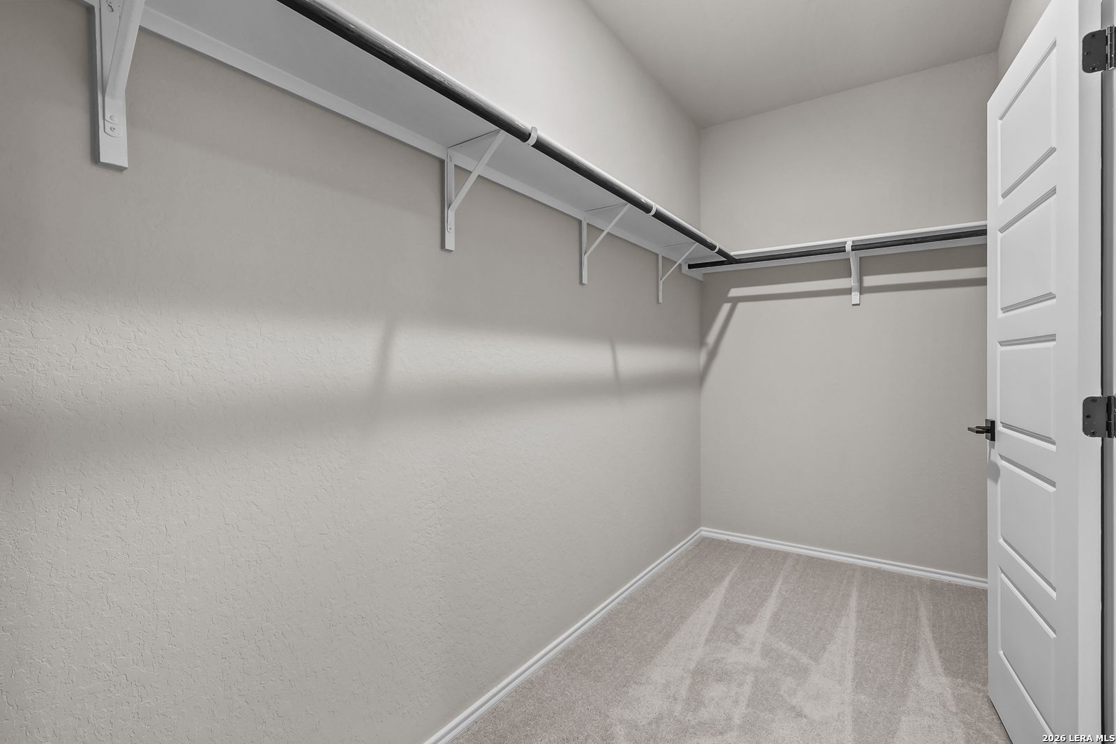 Walk-in closet with shelving and carpeted floors in The Daphne H floor plan, Hannah Heights, Seguin home.