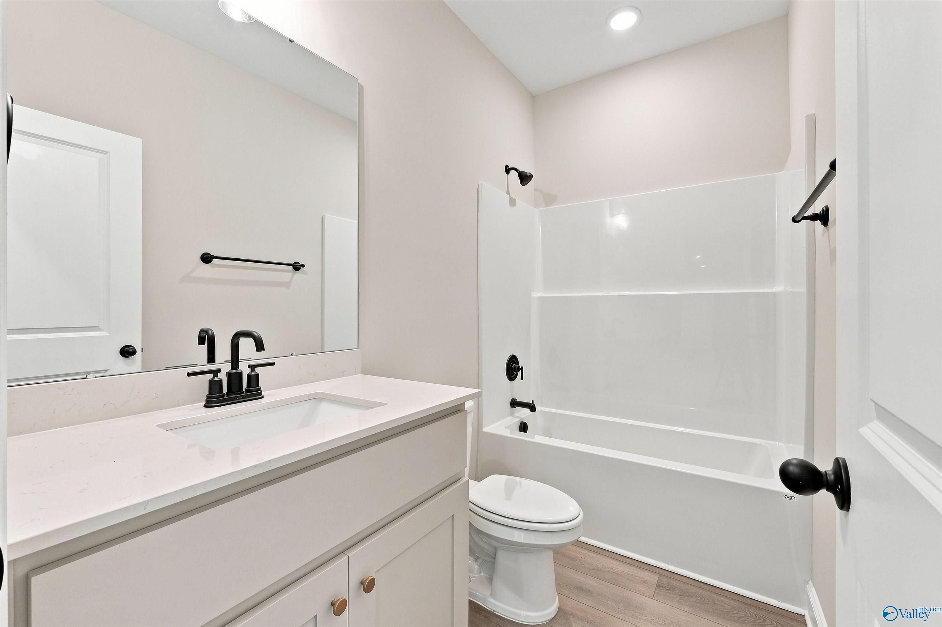 Modern bathroom with white vanity, quartz countertop, and black fixtures in The Oxford floor plan at Kendall Farms, Toney.