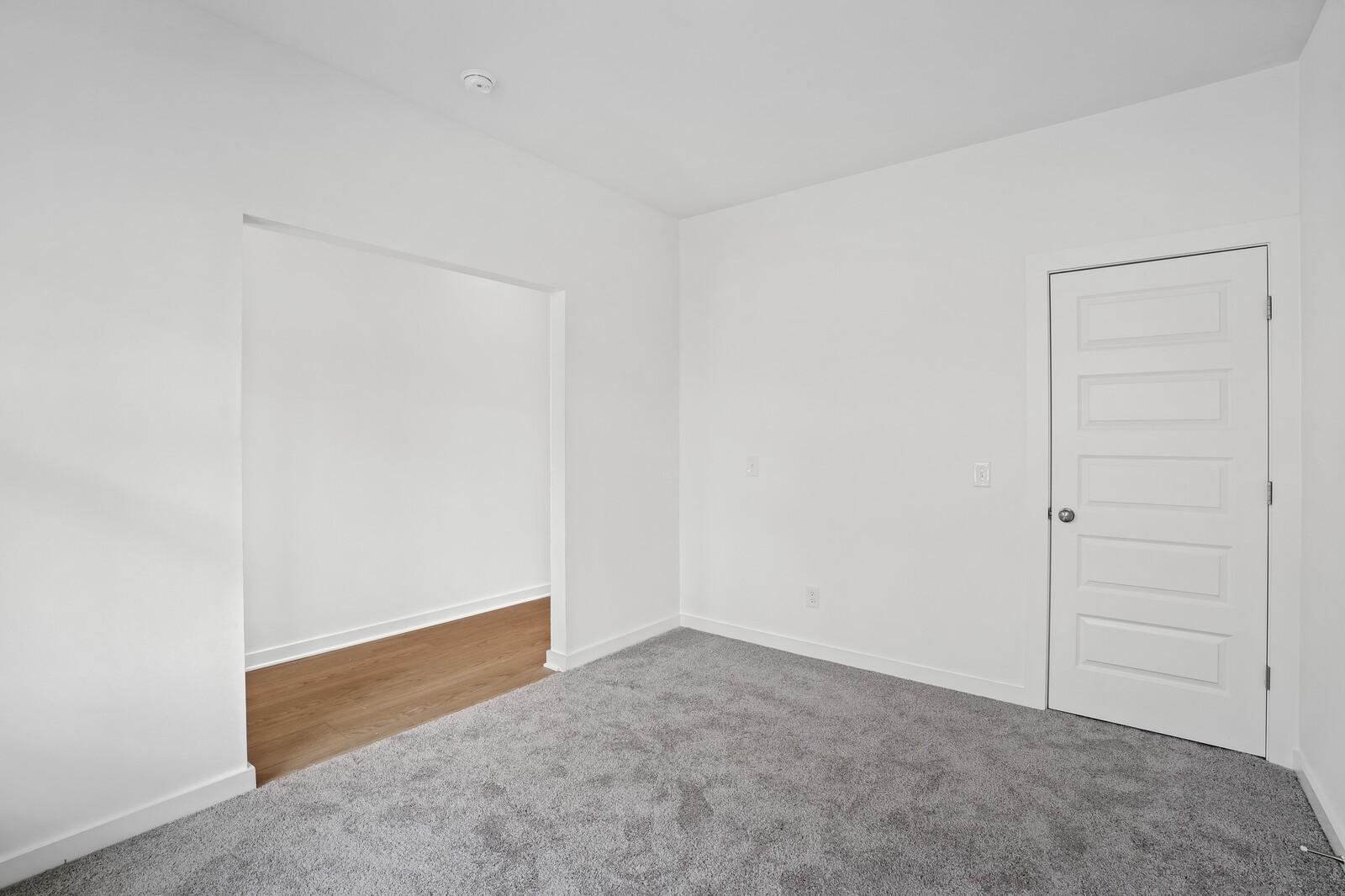 Empty bedroom with white walls, built-in closet, wood base trim, and gray carpet in Davidson Homes The Logan C, White House, TN