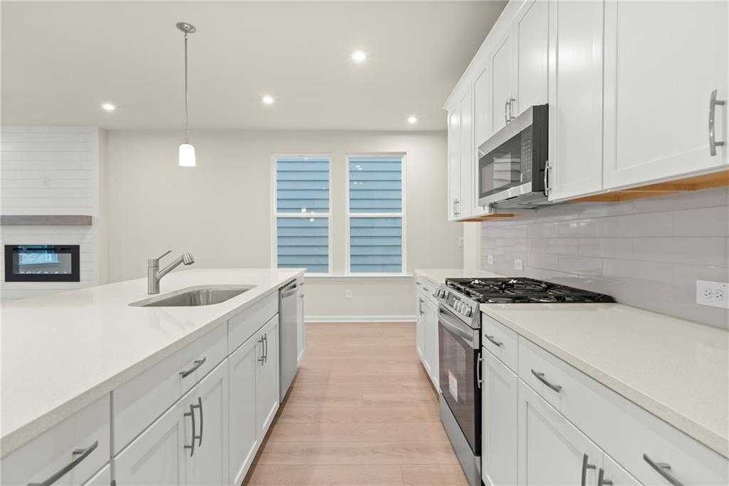 Modern white kitchen with quartz island, stainless appliances, gas range, and subway backsplash in Davidson Homes The Cary A, Kennesaw