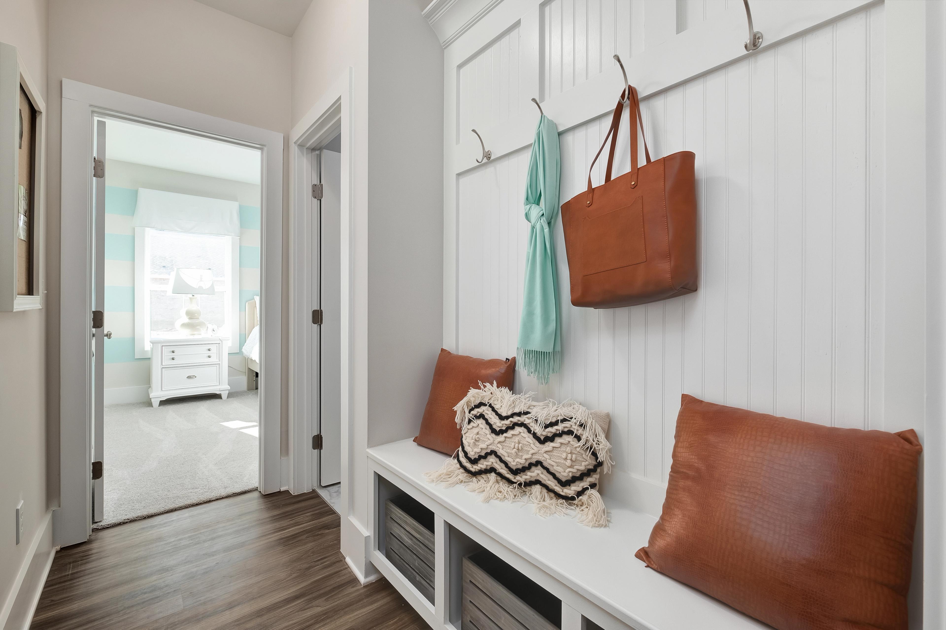 Spacious mudroom entryway at Mallard Landing in Athens Alabama with white beadboard walls, built-in bench, cushions and coat hooks