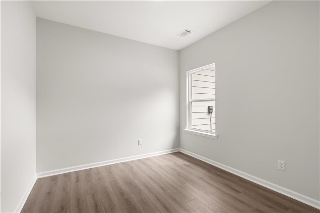 Bright, neutral secondary bedroom with wood-style flooring in The Sinclair B floor plan at Cedar Farms, Winder, Georgia.