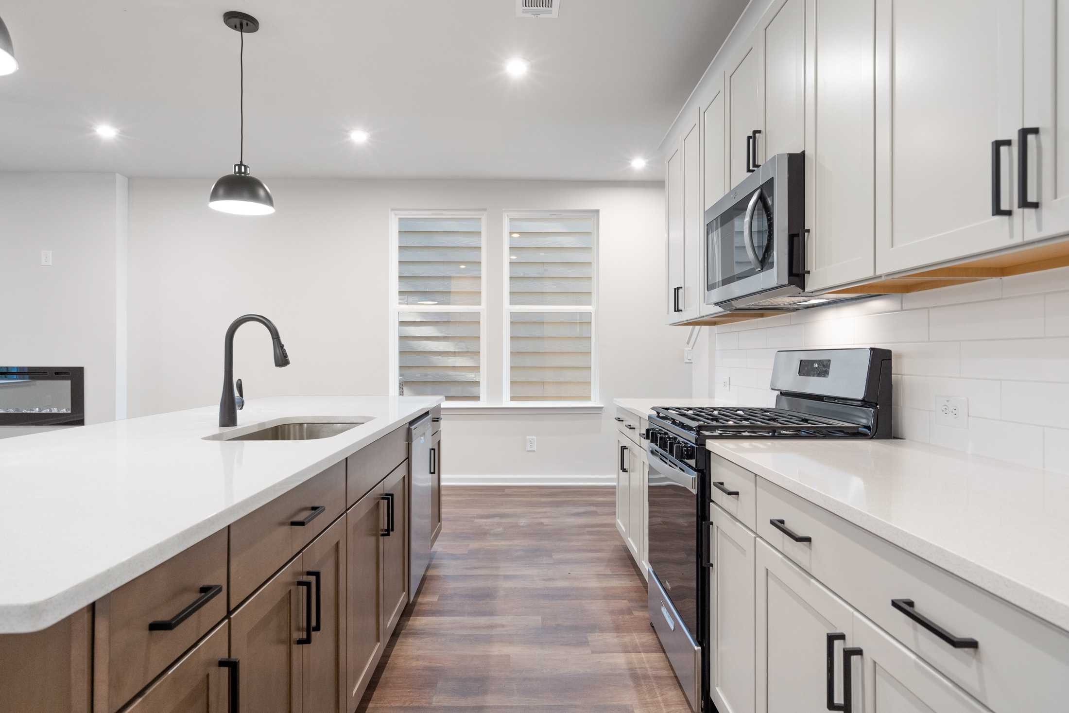 Open-concept kitchen in The Cary B by Davidson Homes, Kennesaw GA, with white shaker cabinets, large island sink, gas range, and stainless appliances