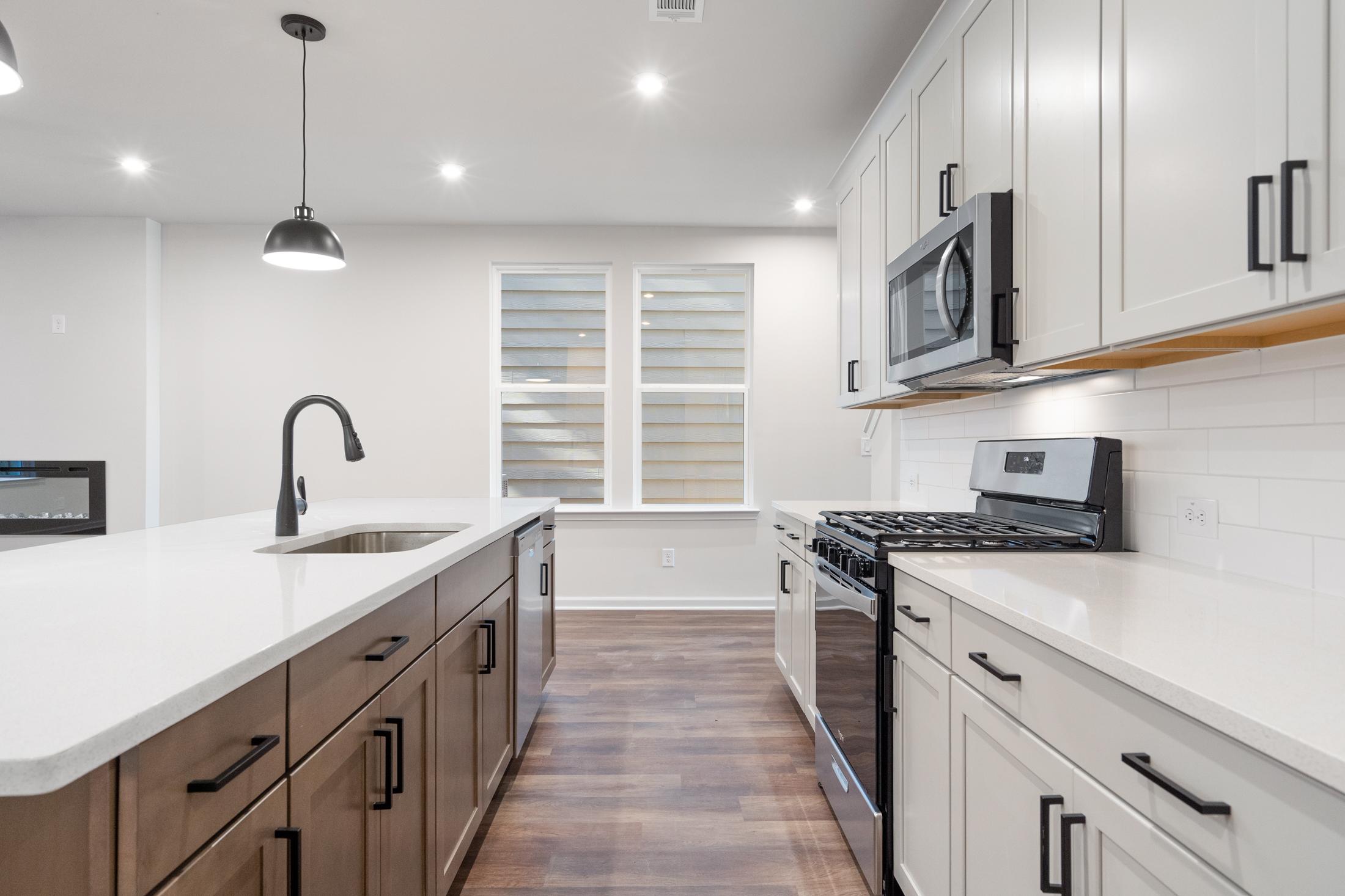 Open-concept kitchen in The Cary B by Davidson Homes, Kennesaw GA, with white shaker cabinets, large island sink, gas range, and stainless appliances