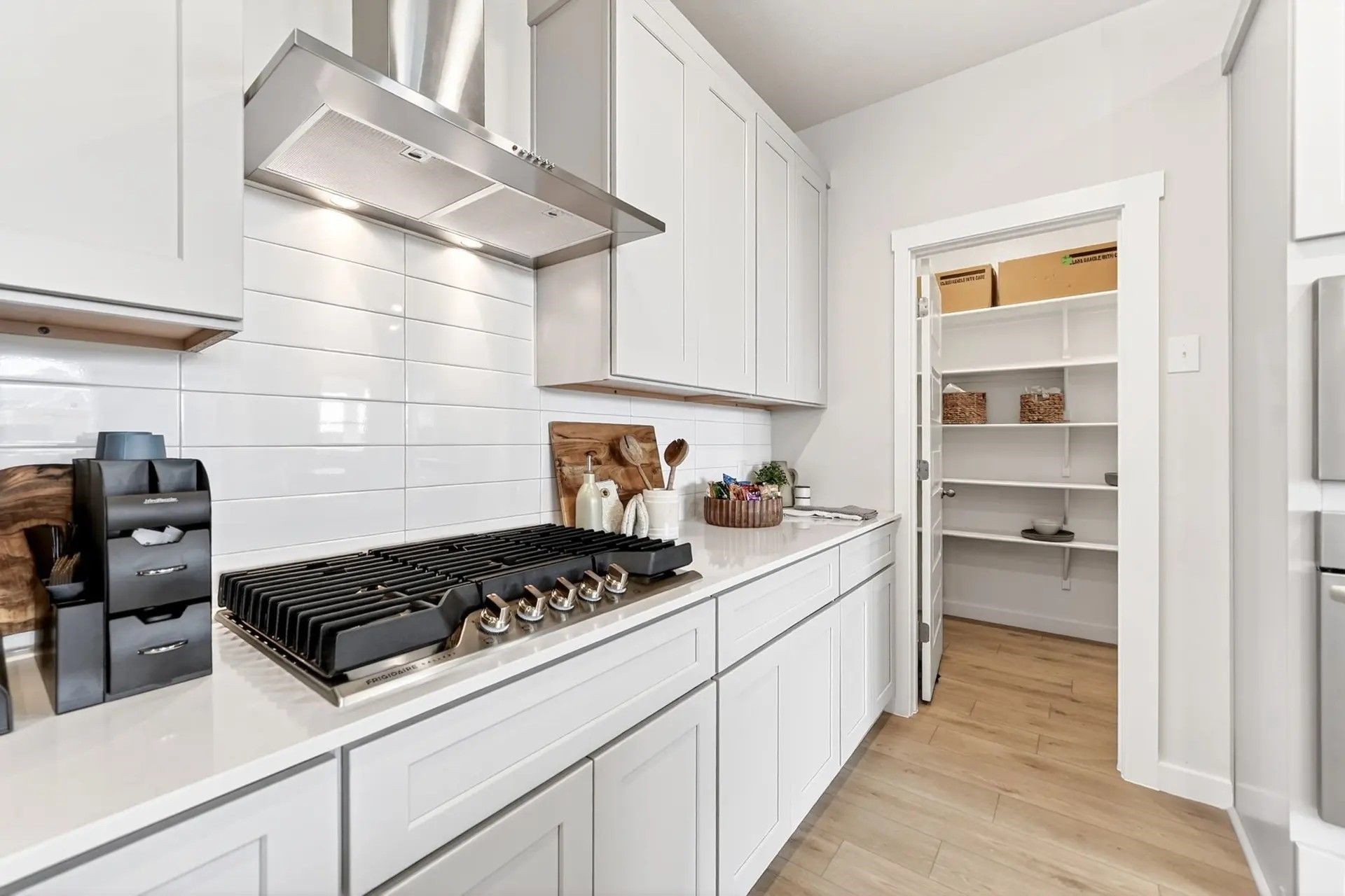 Modern kitchen with white cabinets, gas range, and walk-in pantry in The Laurel I floor plan by Davidson Homes in Heartland.