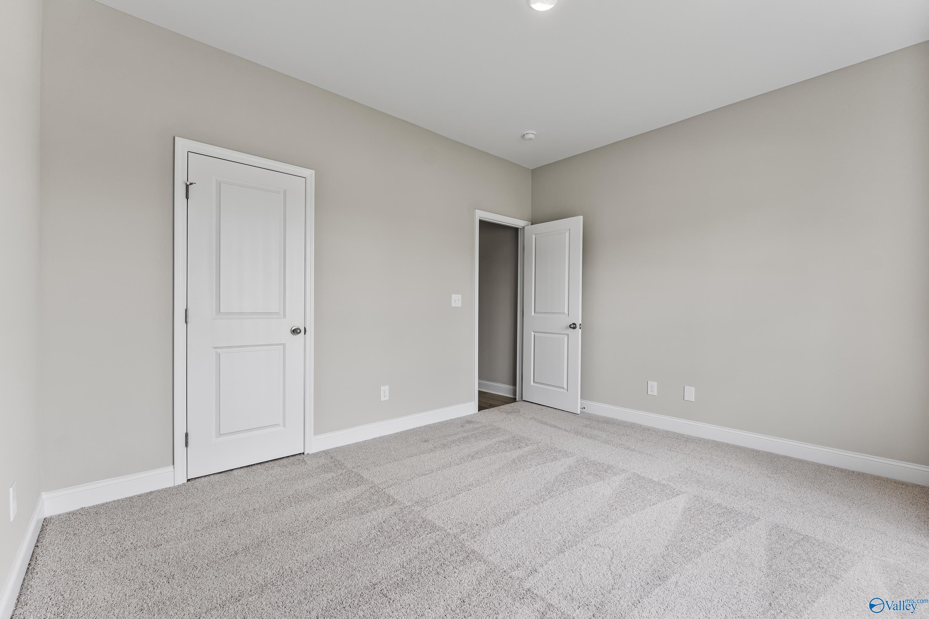 Neutral bedroom with beige walls, white doors, carpet flooring in Davidson Homes The Daphne C, Creekside, Harvest, Alabama
