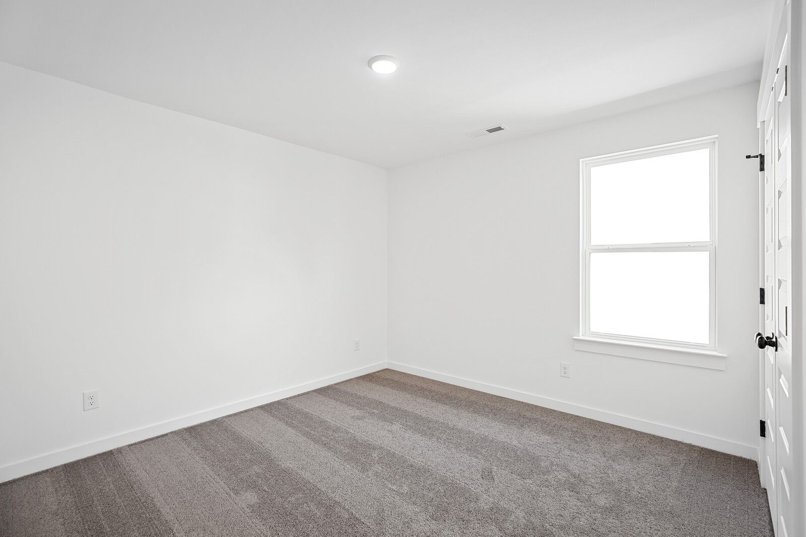 Bright empty bedroom with large window, neutral carpet flooring in The Logan C, Davidson Homes, Gallatin, Tennessee