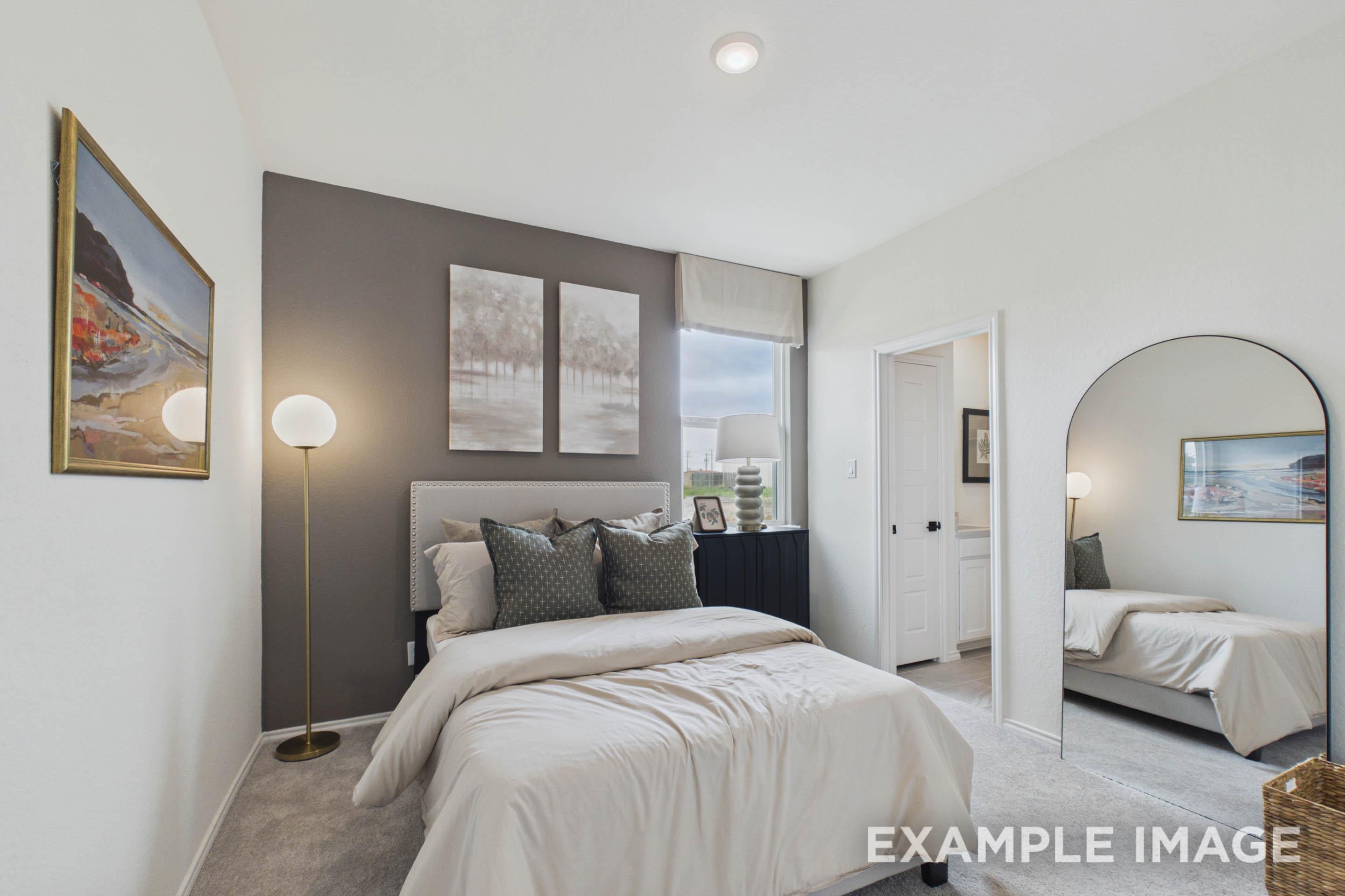 Modern secondary bedroom in The Laurel G floor plan featuring a gray accent wall, plush bedding, and an arched floor mirror.