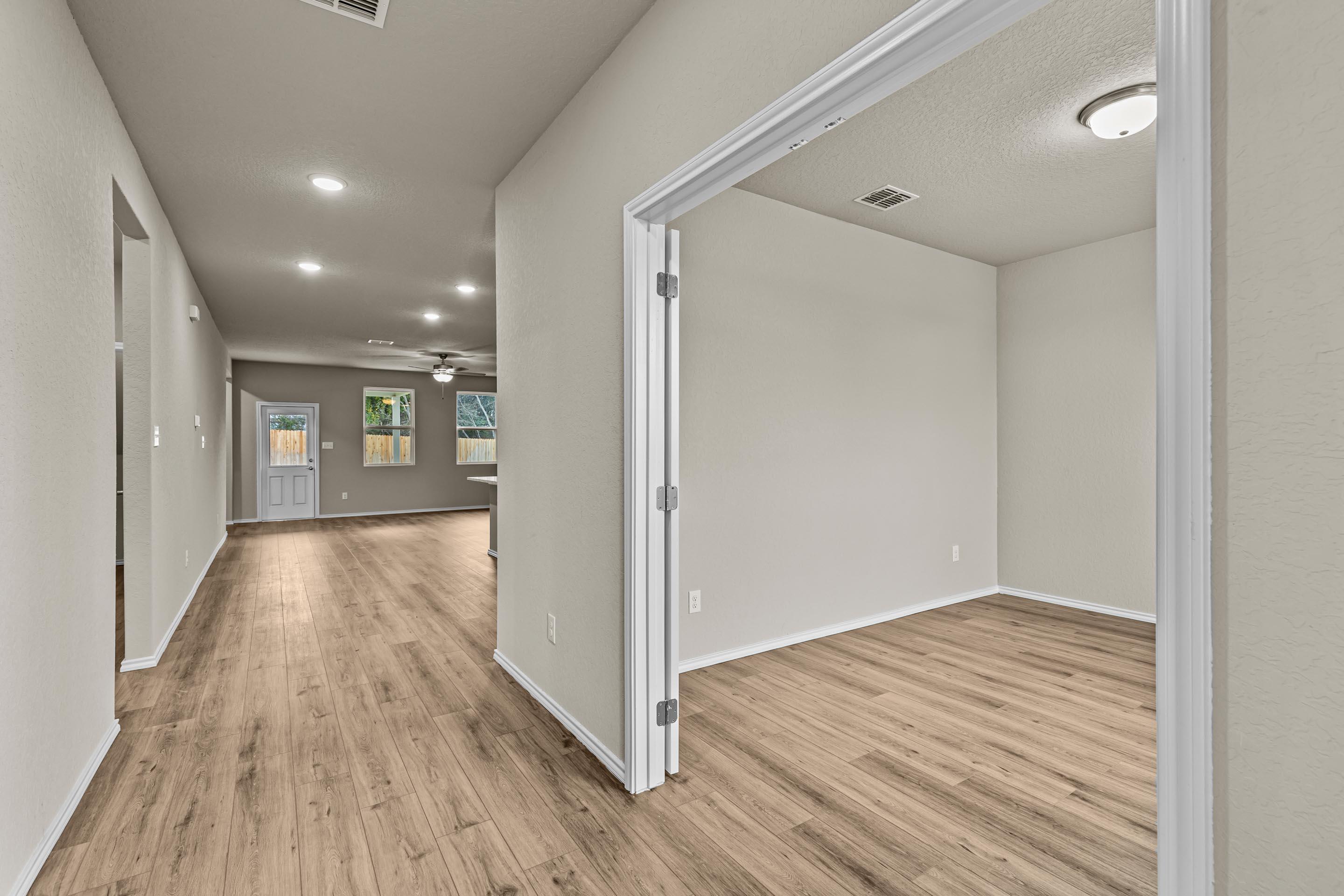 Bright hallway with light oak hardwood floors, open doorways to study and rooms in Davidson Homes The Douglas F, Royal Crest, San Antonio