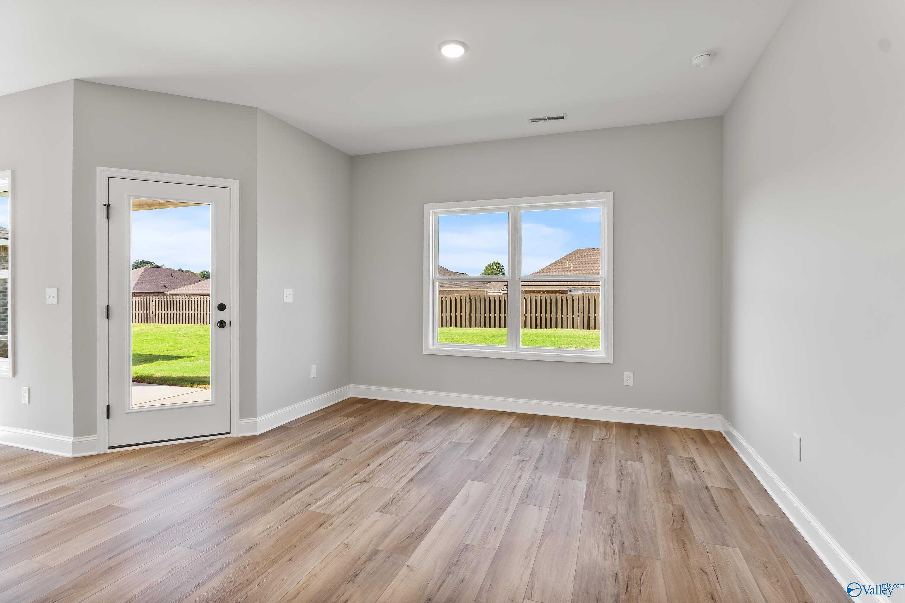 Bright living room with hardwood floors, gray walls, large windows and glass door overlooking fenced backyard in Davidson Homes The Franklin B, Hazel Green, AL
