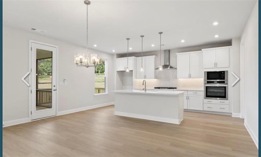 Modern open-concept kitchen with white island, stainless appliances, hardwood floors in Davidson Homes The Hampton C, Buford, GA