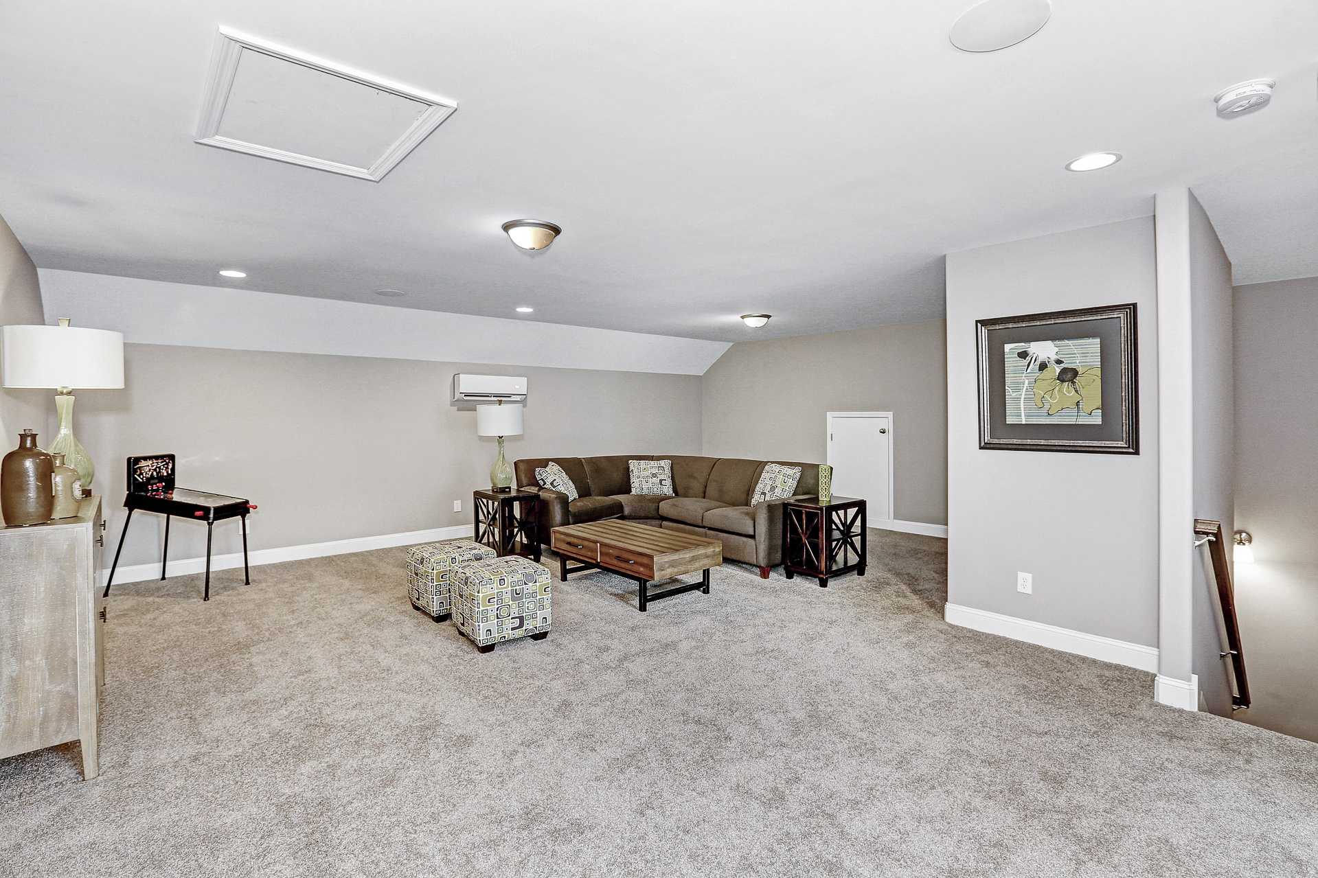 Spacious bonus room with L-shaped sectional sofa, neutral beige carpet and walls at Stone Creek Phase II in Cullman AL by Davidson Homes