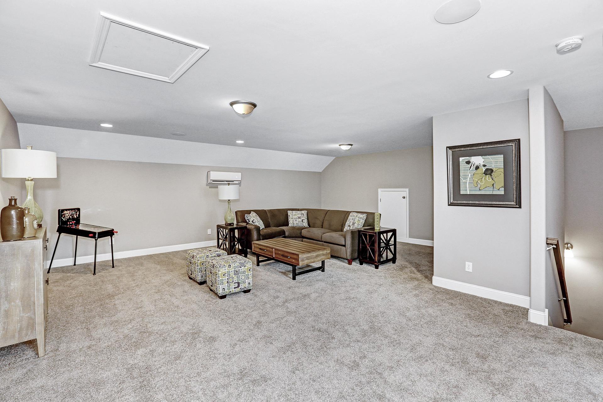 Spacious bonus room with L-shaped sectional sofa, neutral beige carpet and walls at Stone Creek Phase II in Cullman AL by Davidson Homes