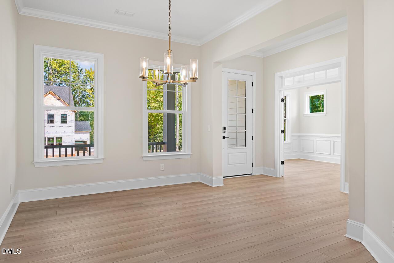 Bright dining room with hardwood floors, modern chandelier, and glass-panel front door in Davidson Homes Crawford D plan, Wake Forest, NC