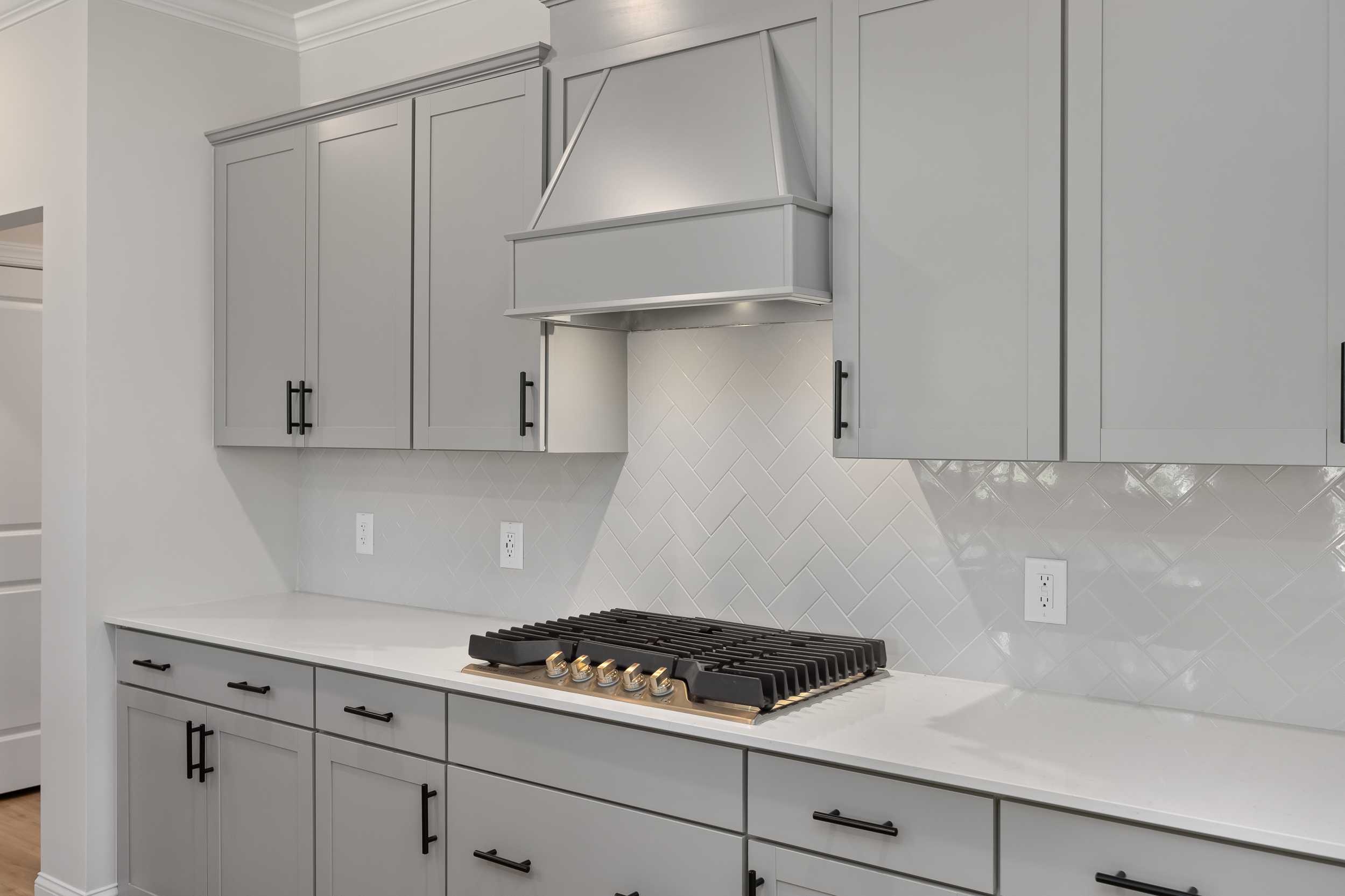 Modern kitchen in The Beech C by Davidson Homes featuring gray shaker cabinets, white quartz counters, and gas range