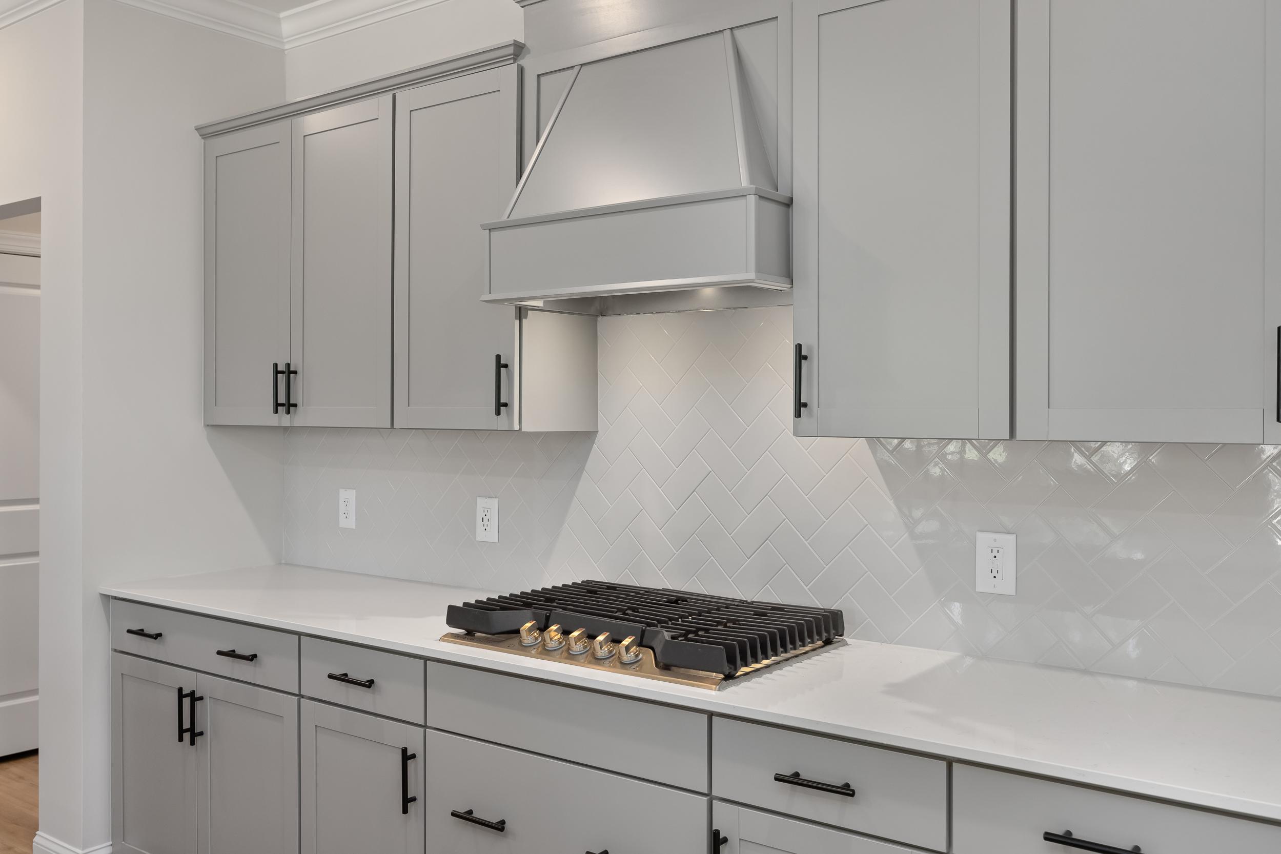 Modern kitchen in The Beech A by Davidson Homes featuring gray shaker cabinets, white quartz counters, and gas range