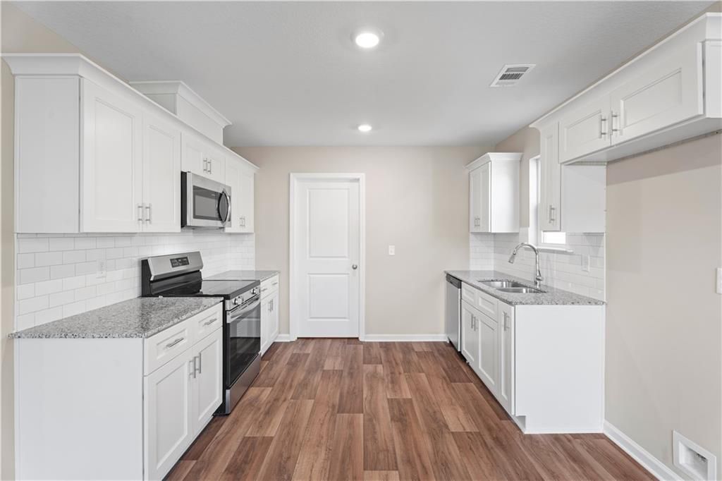 Modern kitchen featuring white cabinets, granite countertops, stainless steel appliances, subway tile backsplash in The Washington home, Phenix City, AL