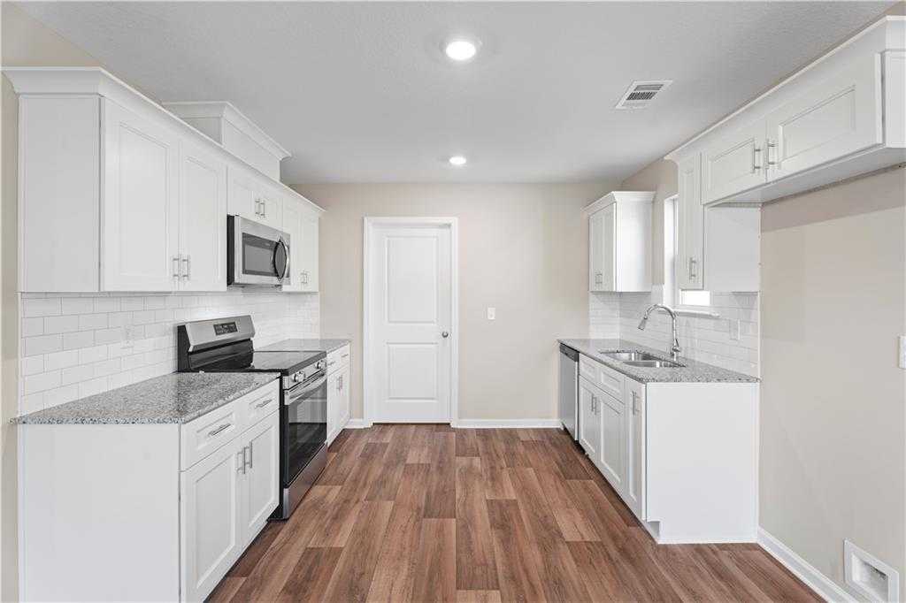 Modern white kitchen with granite counters, stainless appliances, subway tile backsplash in Davidson Homes The Washington, Phenix City, AL