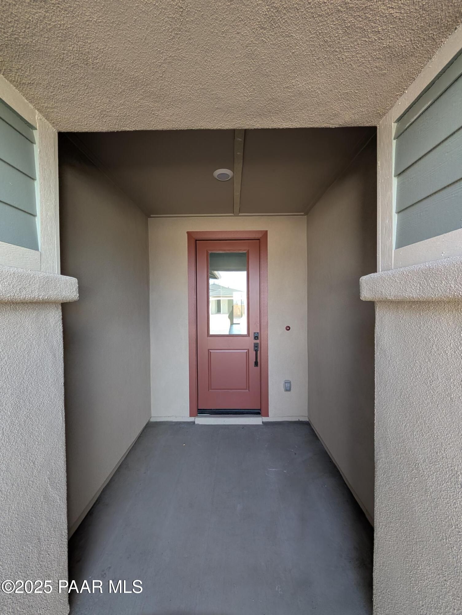 Modern entry hallway with wooden front door, beige stucco walls, and concrete floor in Davidson Homes The Sheridan II F, Prescott, Arizona