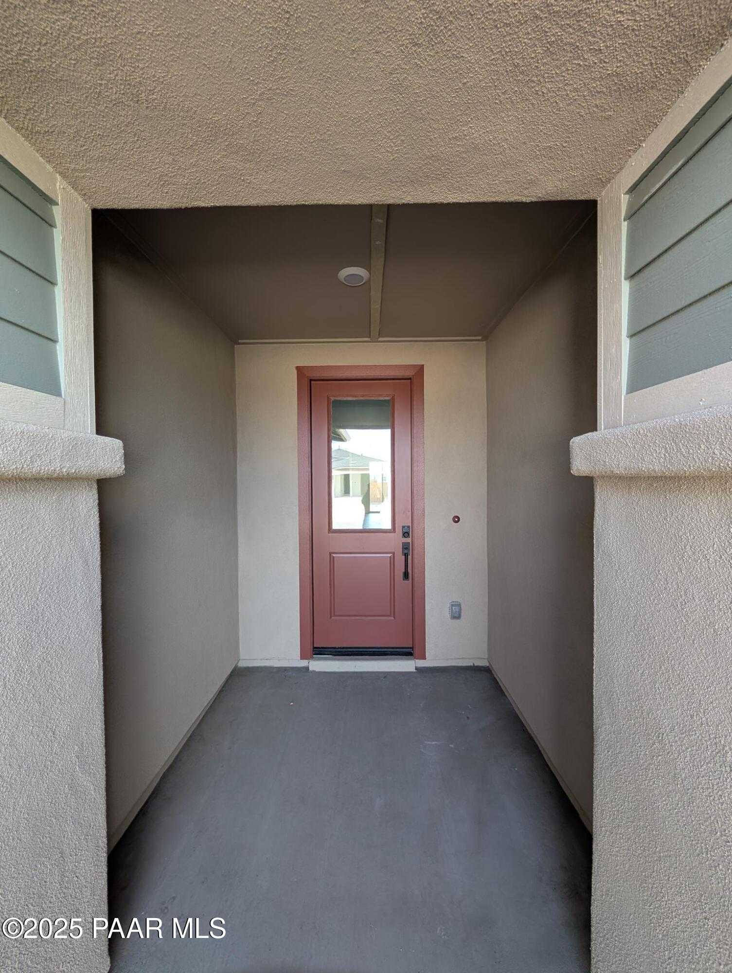 Modern entry hallway with wooden front door, beige stucco walls, and concrete floor in Davidson Homes The Sheridan II F, Prescott, Arizona