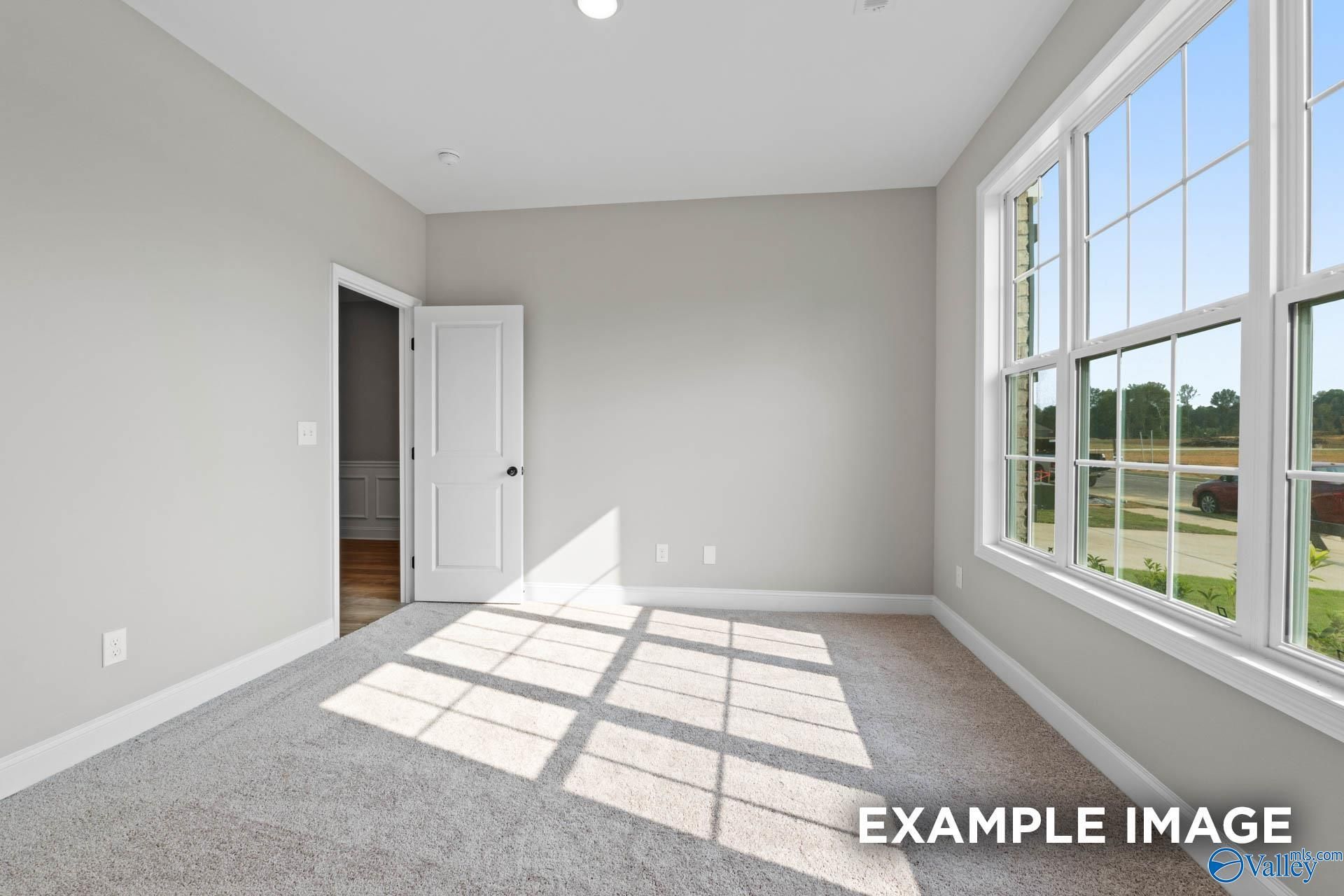 Bright bedroom with light gray walls, large sunny windows, and carpet floor in Davidson Homes The Montgomery B, Toney, Alabama