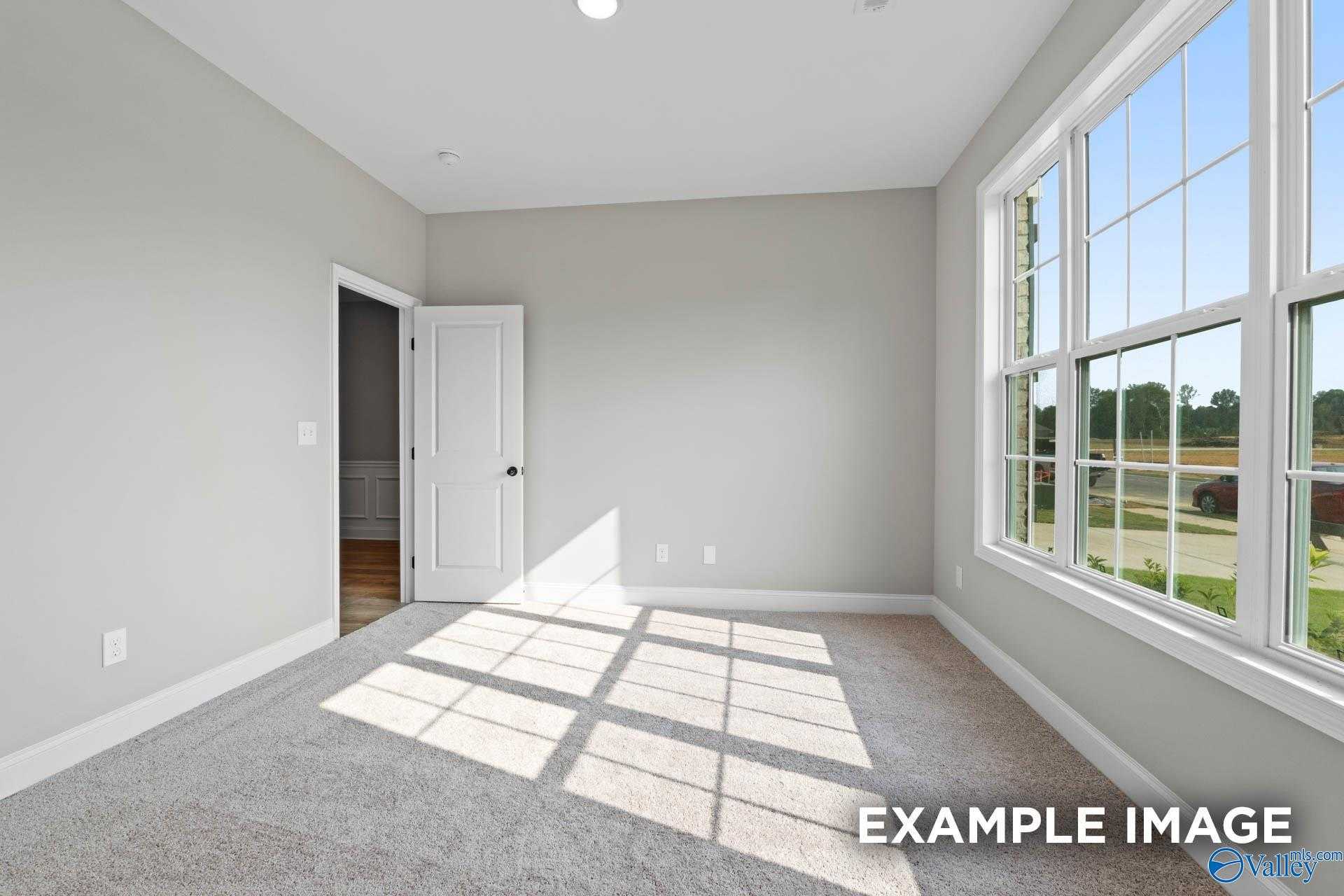 Bright bedroom with light gray walls, large sunny windows, and carpet floor in Davidson Homes The Montgomery B, Toney, Alabama