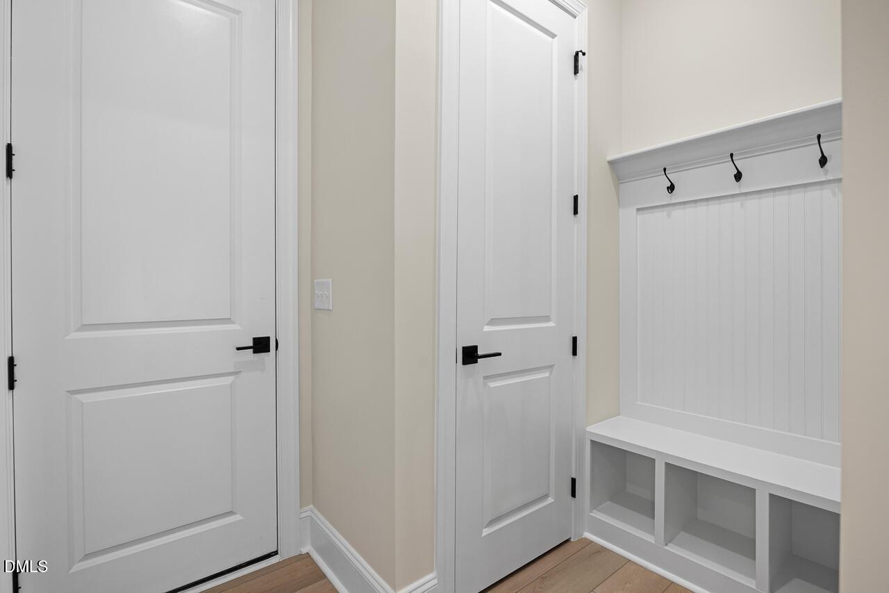 Mudroom with built-in bench, coat hooks, and white doors in Davidson Homes The Crawford D floor plan at Rockport, Wake Forest, NC