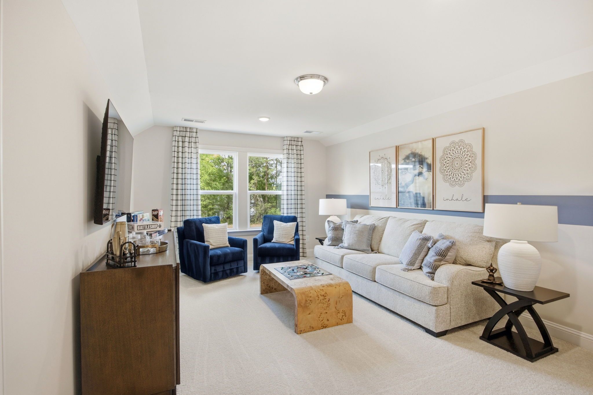 Cozy family room at Enclave at Belmont in Belmont NC with beige sectional sofa, blue velvet chairs, burl wood coffee table, and wall art