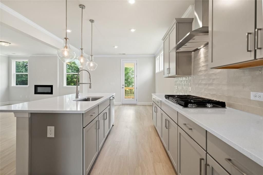 Modern kitchen with white shaker cabinets, quartz island, stainless appliances, subway tile backsplash in Davidson Homes The Willow D at Wehunt Meadows, Hoschton, GA